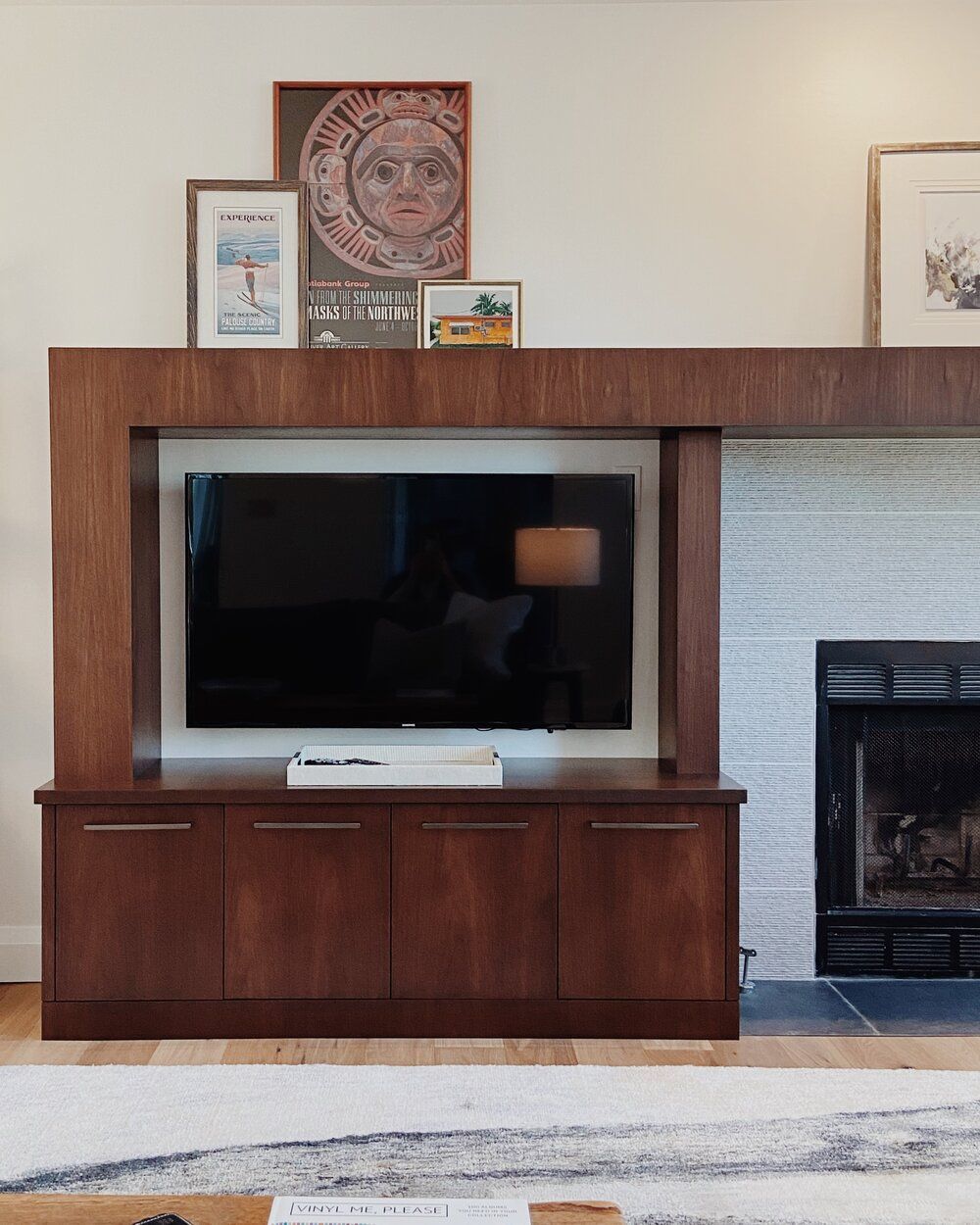 Living room wall with a flat-screen TV, fireplace, and framed art above a wooden cabinet
