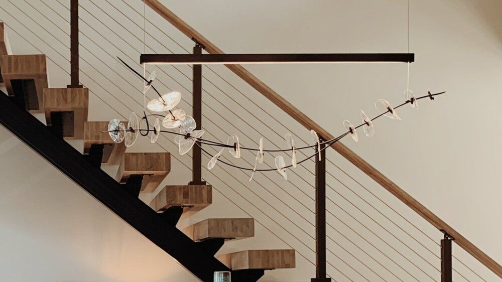 Spiral staircase with a wall-mounted glass-and-metal railing and a dark horizontal handrail
