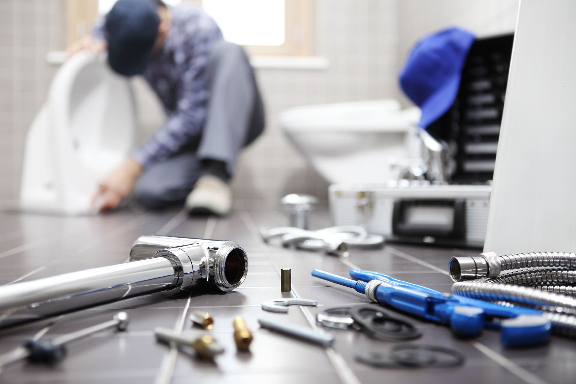 Plumber tools on a table with a worker fixing pipes in a blurred background