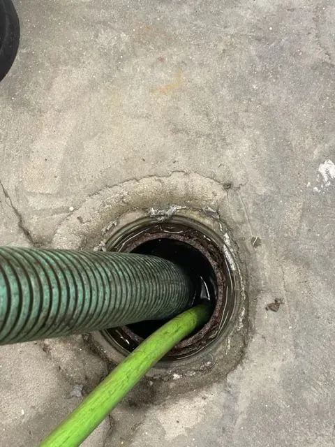 Green hoses going through a circular hole in a concrete floor