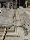 A concrete walkway is being built in front of a house.
