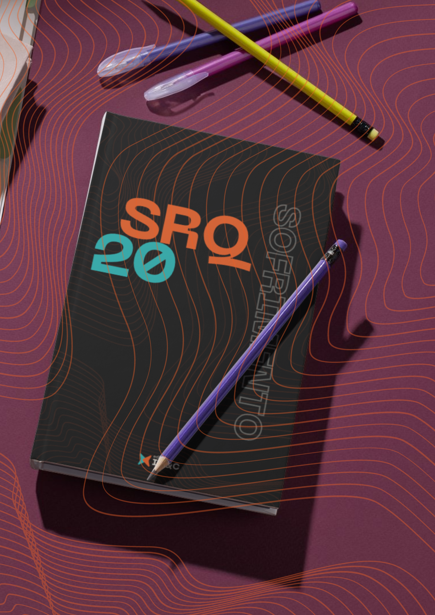 Caderno SRQ 20 com canetas e lápis sobre fundo estampado marrom.