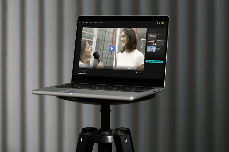 Laptop em tripé mostrando uma interface de edição de vídeo com uma pessoa na tela.
