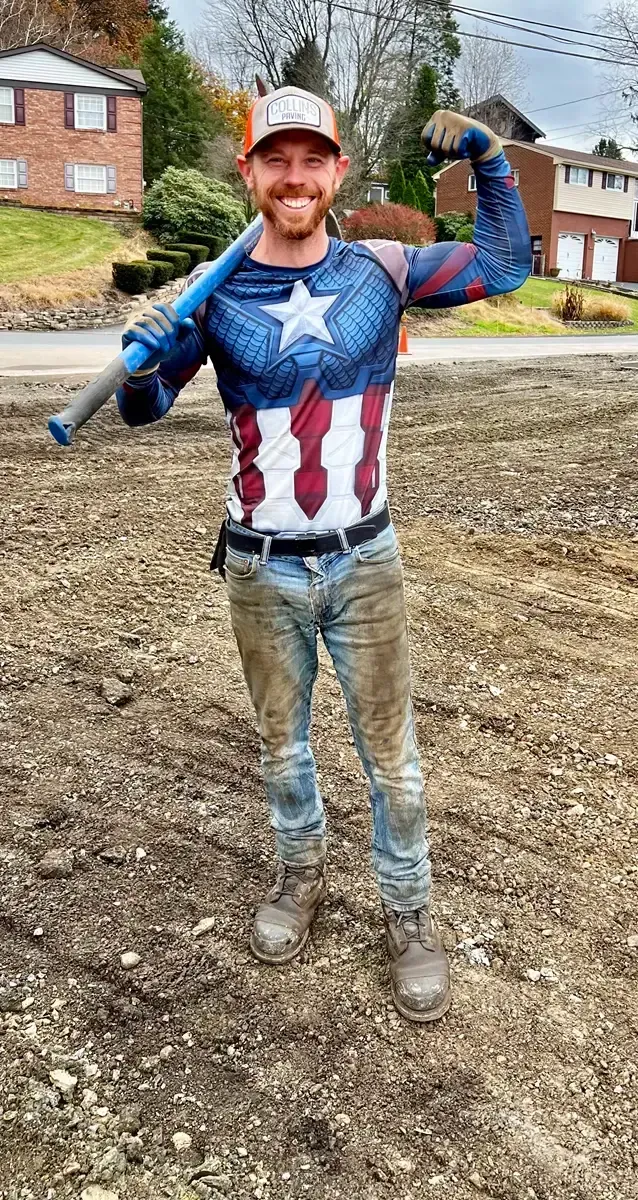 A man in a captain america costume is holding a mattock