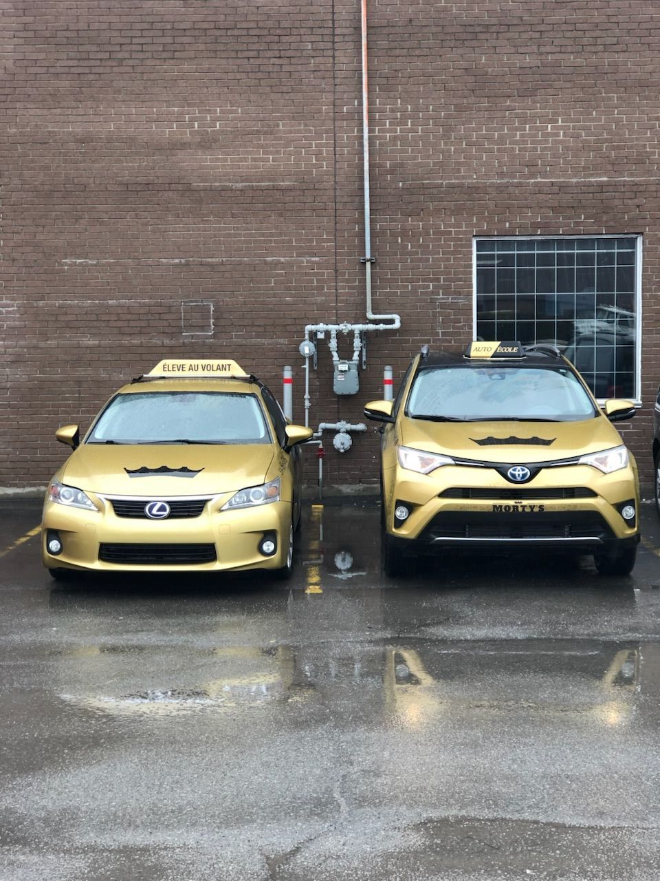 Deux taxis de couleur or étaient garés devant un bâtiment en briques.