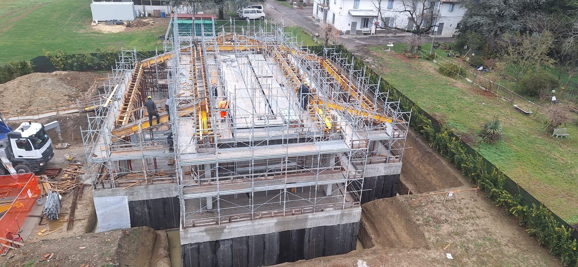 Cantiere edile con fondamenta in cemento e impalcature, visto dall’alto
