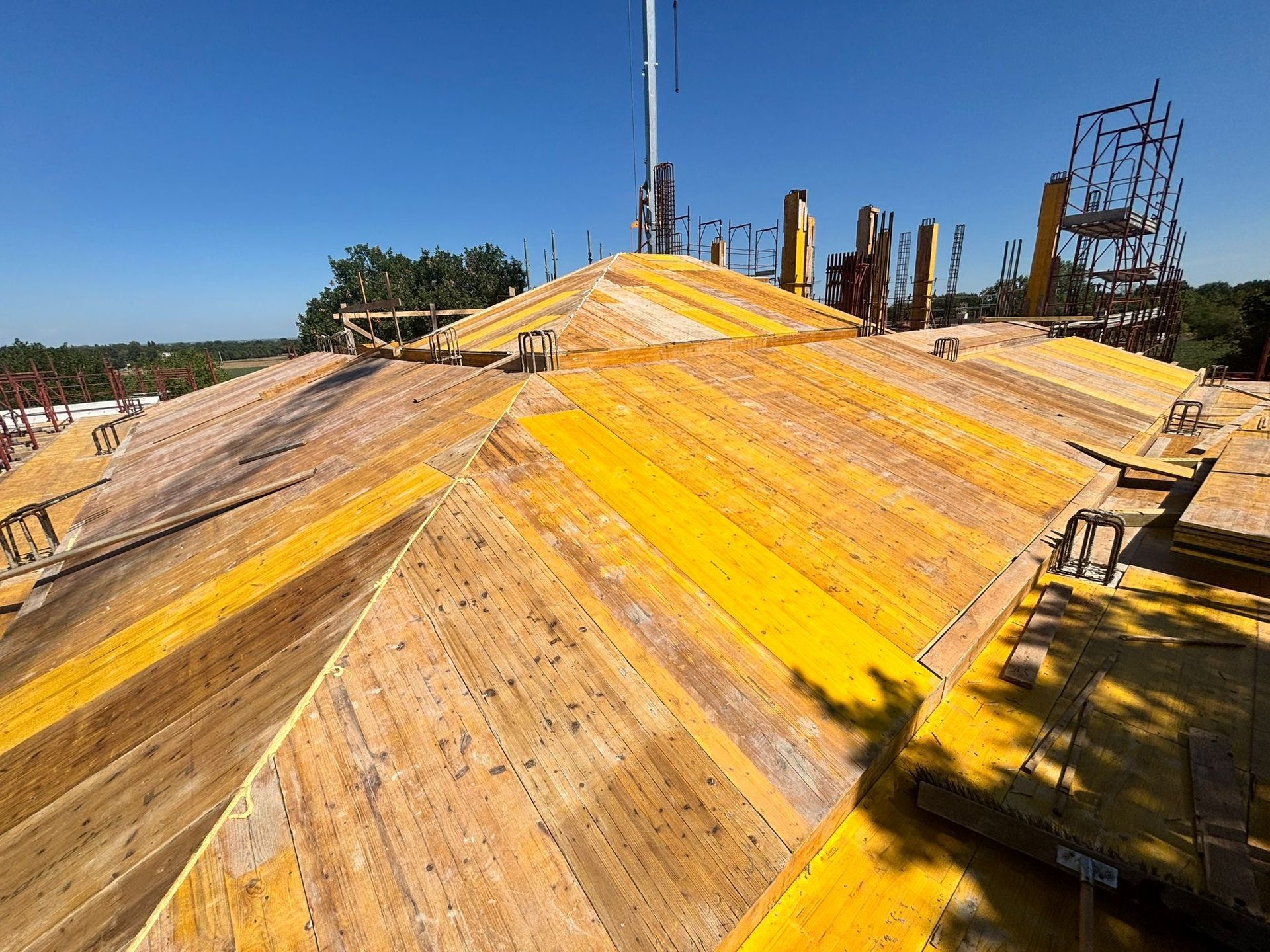 Tetto in legno a strisce gialle, con ferri d’armatura da costruzione e cielo azzurro terso