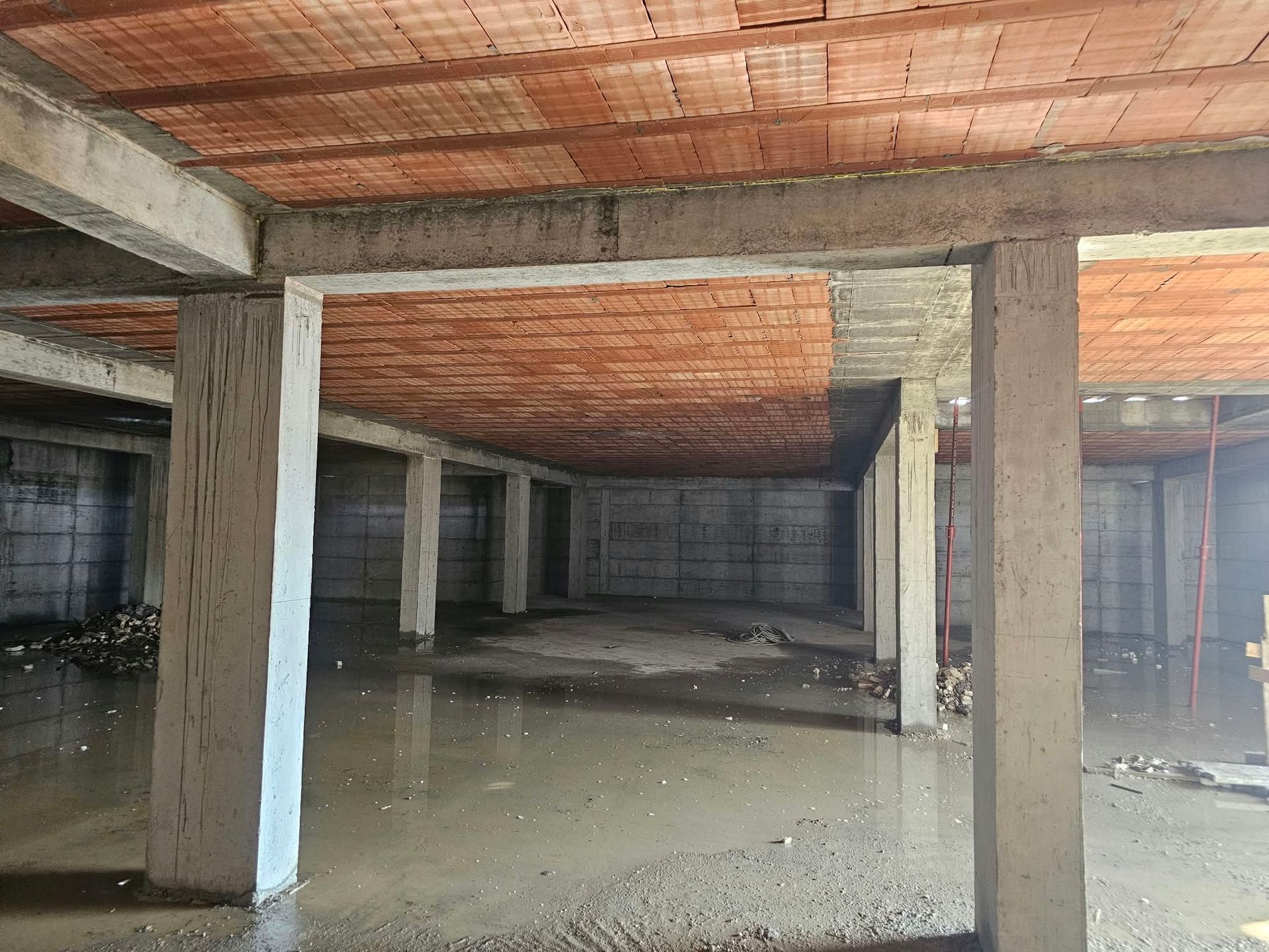 Seminterrato in cemento vuoto e non finito, con colonne portanti e soffitto in mattoni a vista