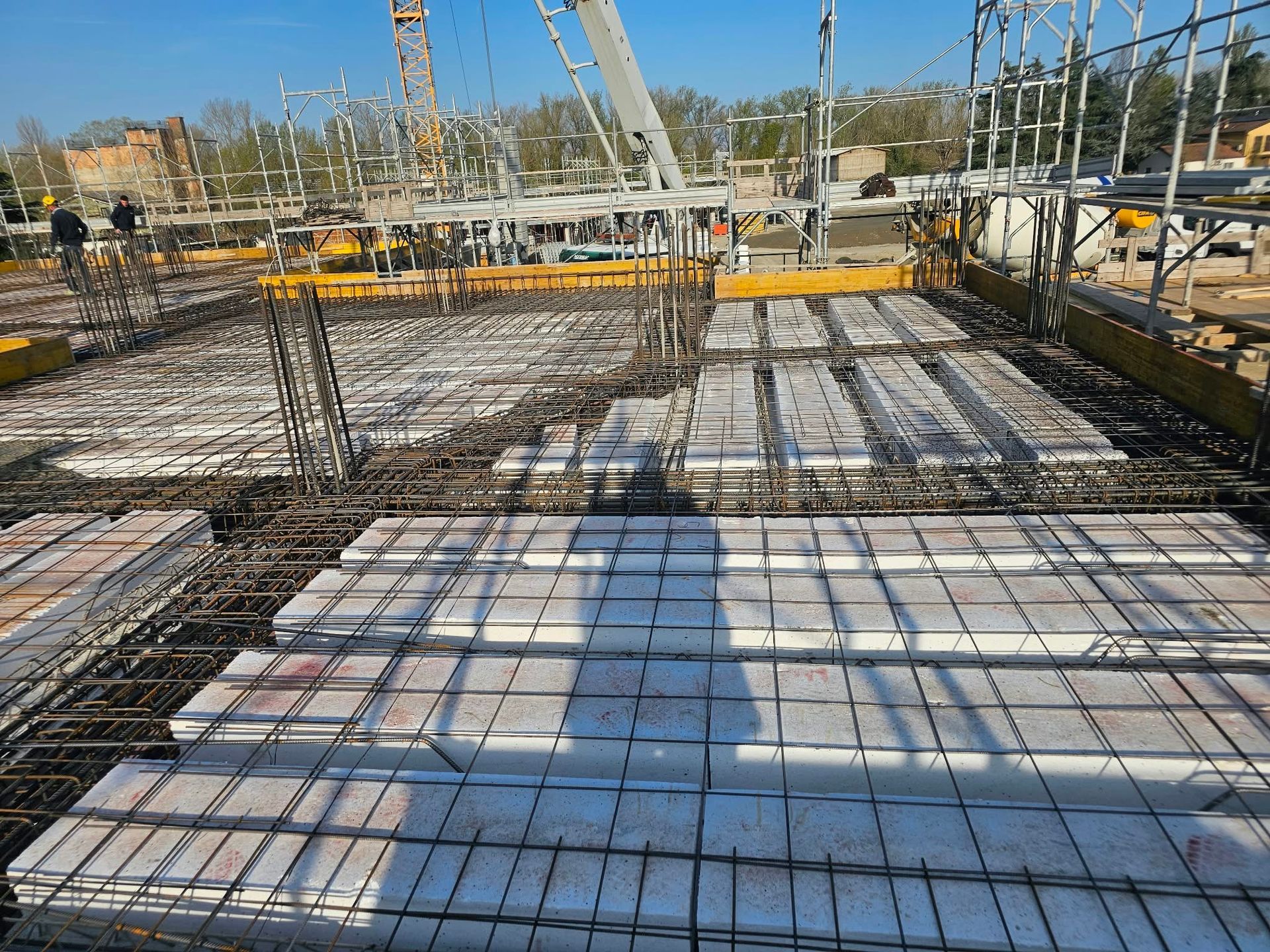 Cantiere con rete di armature e casseforme in cemento, visto da un ponte in costruzione