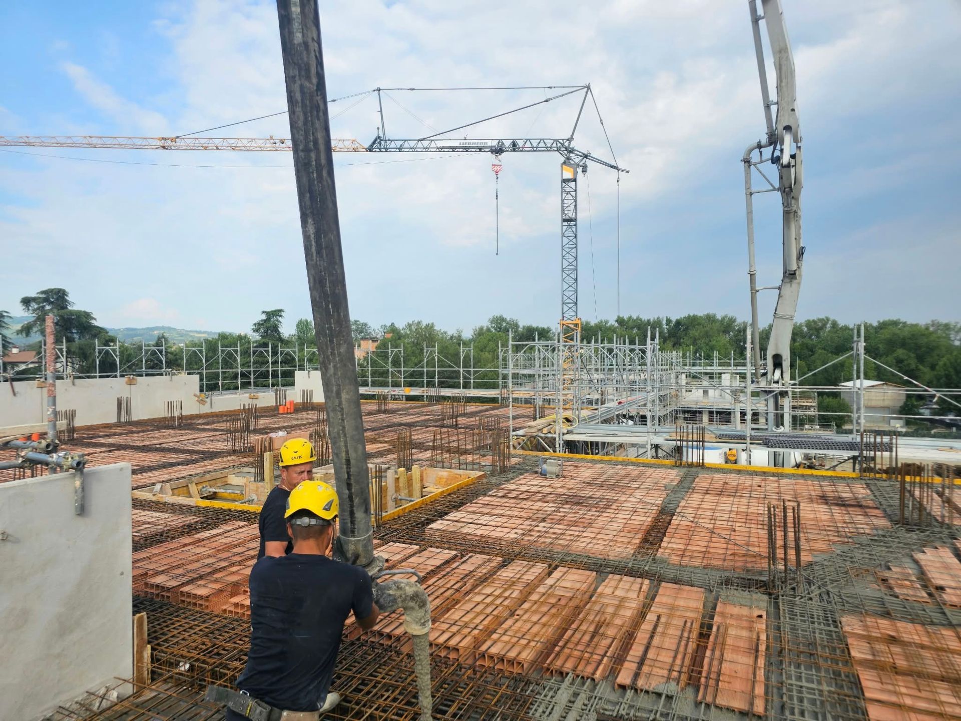 Operai edili su un solaio di armatura in ferro sul tetto, con gru e materiali da costruzione nelle vicinanze