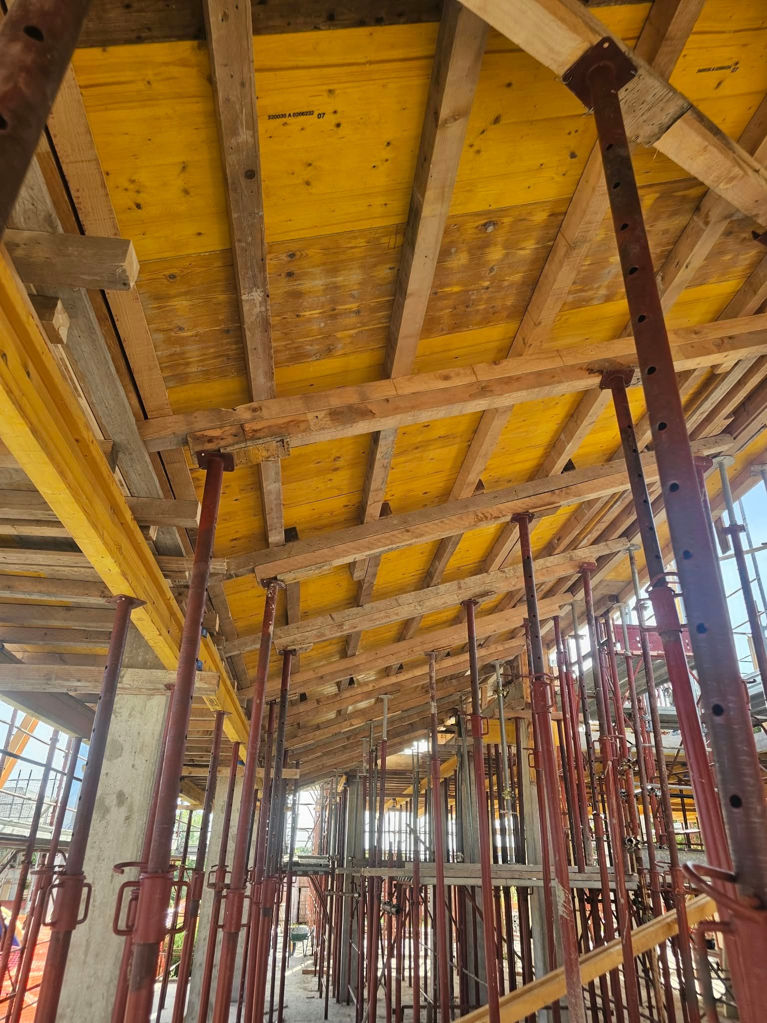 Interno di un cantiere con casseri per il soffitto in compensato giallo e puntelli di sostegno in acciaio rosso