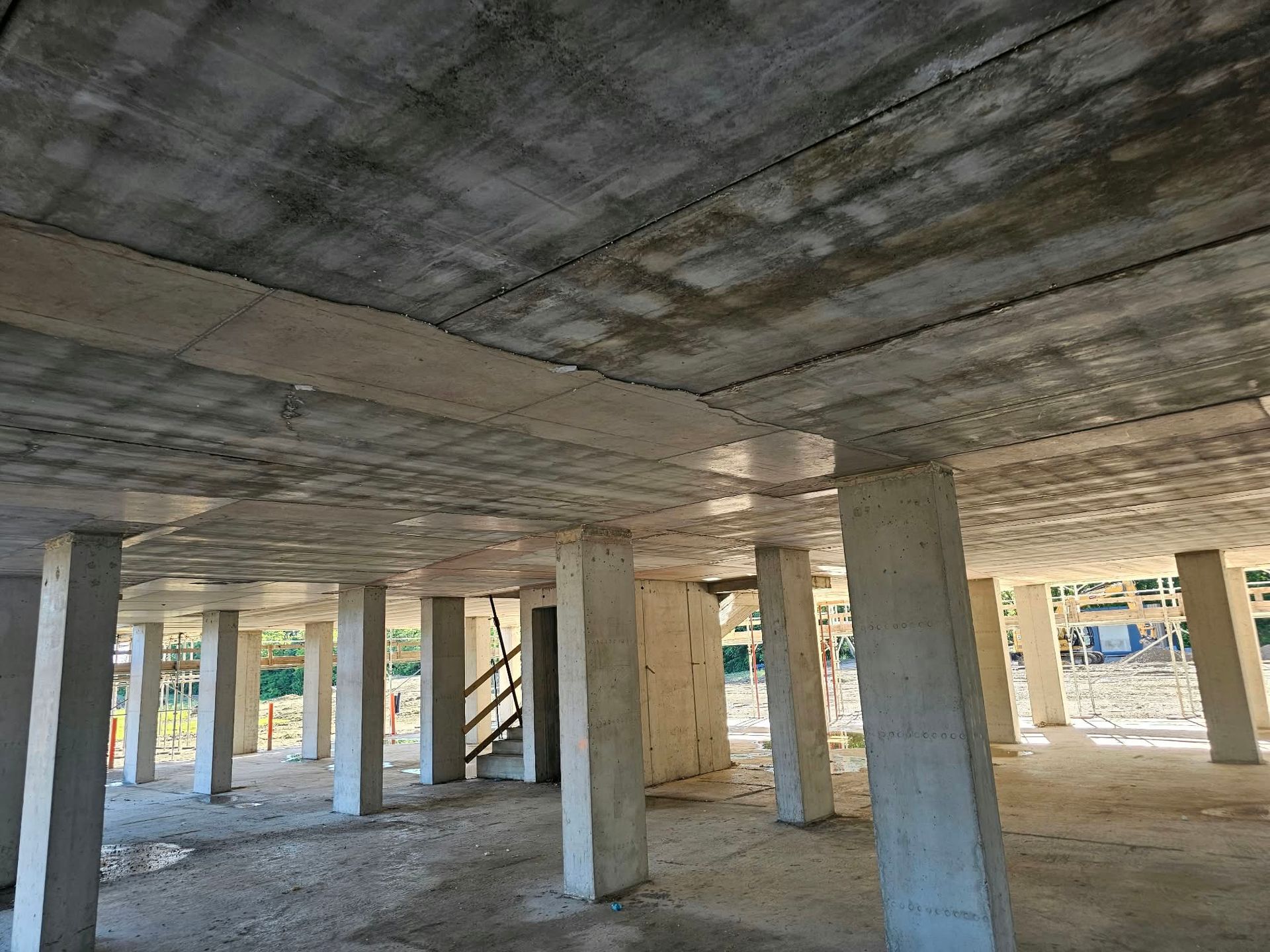Struttura di parcheggio in cemento armato, vuota e incompiuta, con colonne e travi a soffitto.