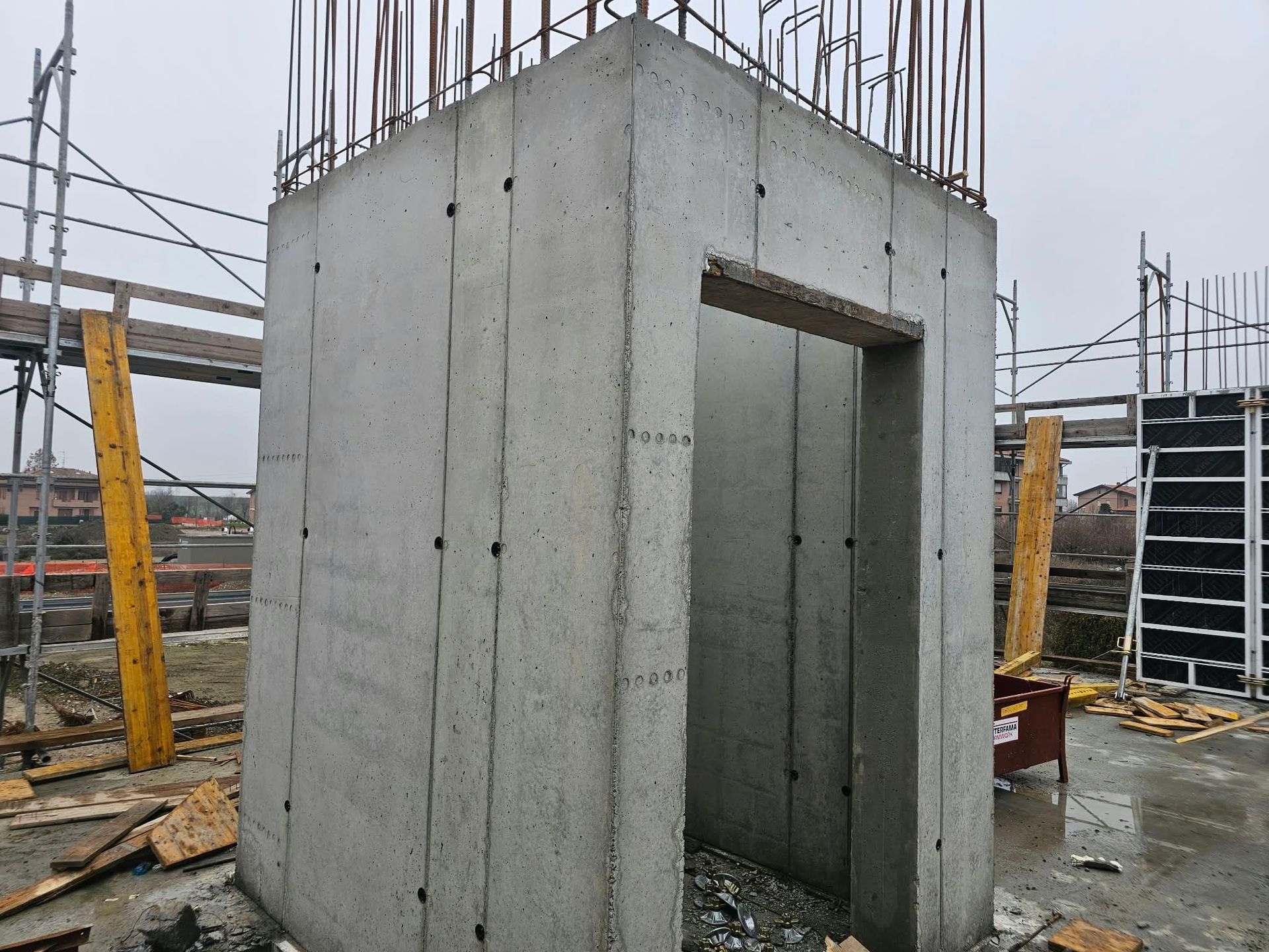 Struttura di un edificio in cemento armato in costruzione, con un’apertura per una porta e i ferri d’armatura a vista sulla sommità