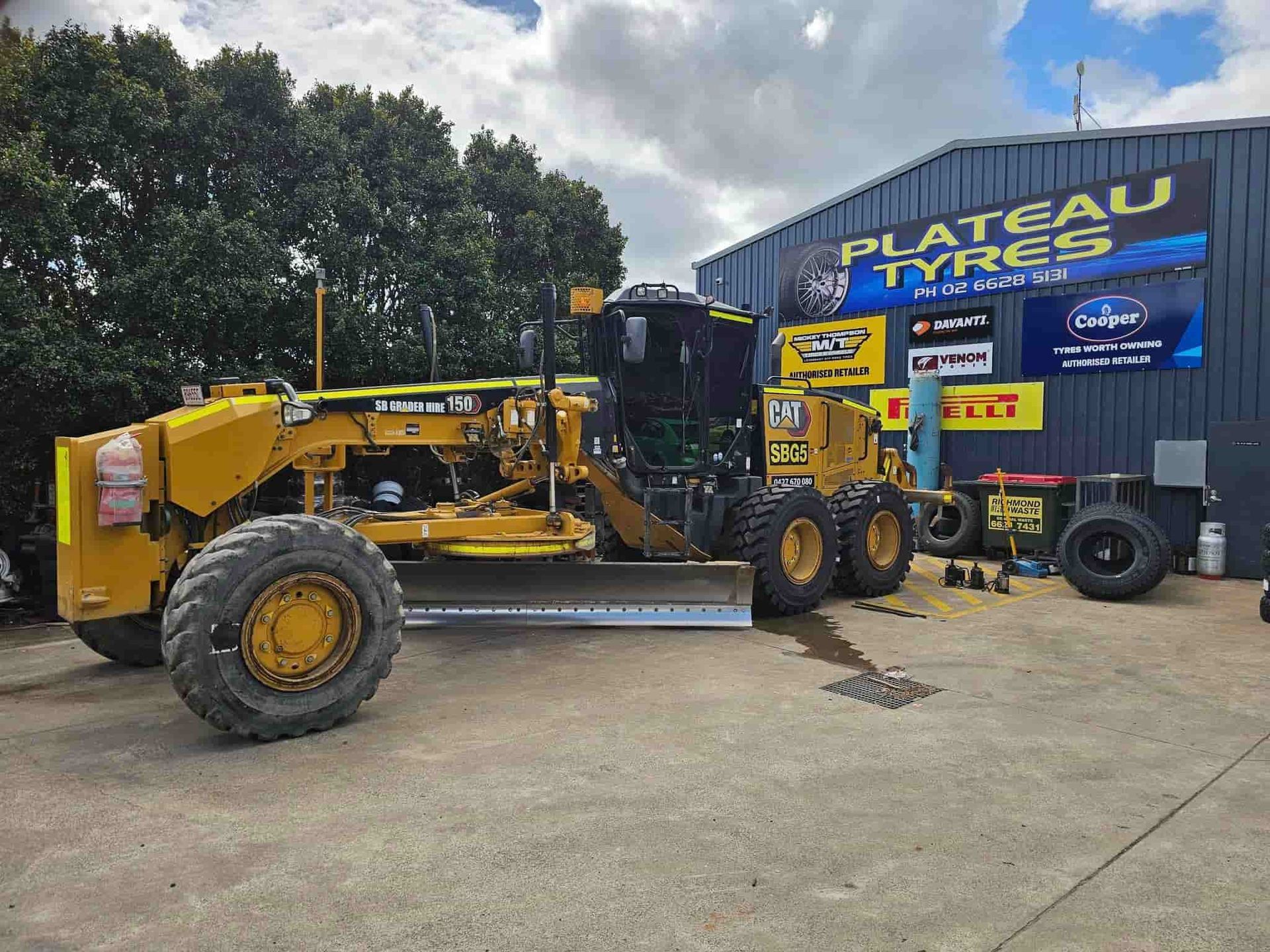 Yellow Caterpillar Road Grader Parked in Front of Plateau Tyres Building — Plateau Tyres in Alstonville, NSW