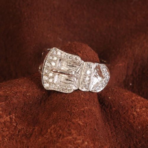 Silver ring with small diamonds on brown fabric.