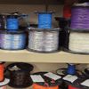A shelf filled with spools of wire of different colors