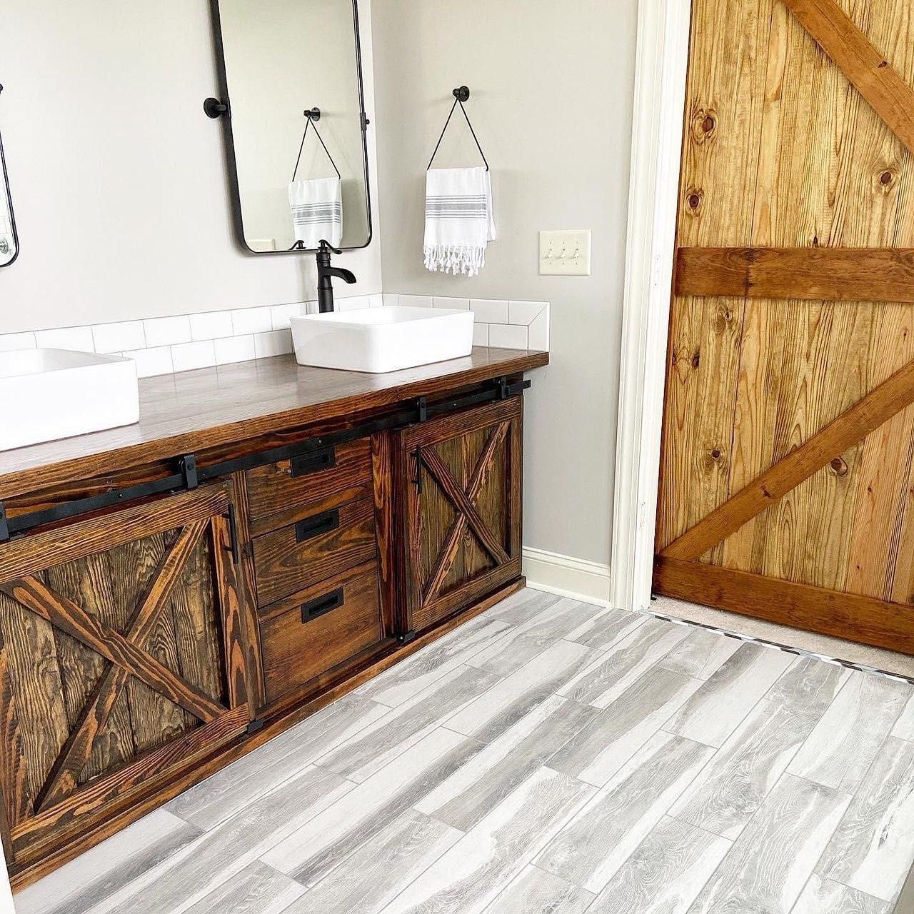 Bathroom with wooden vanity, barn door, and gray flooring.
