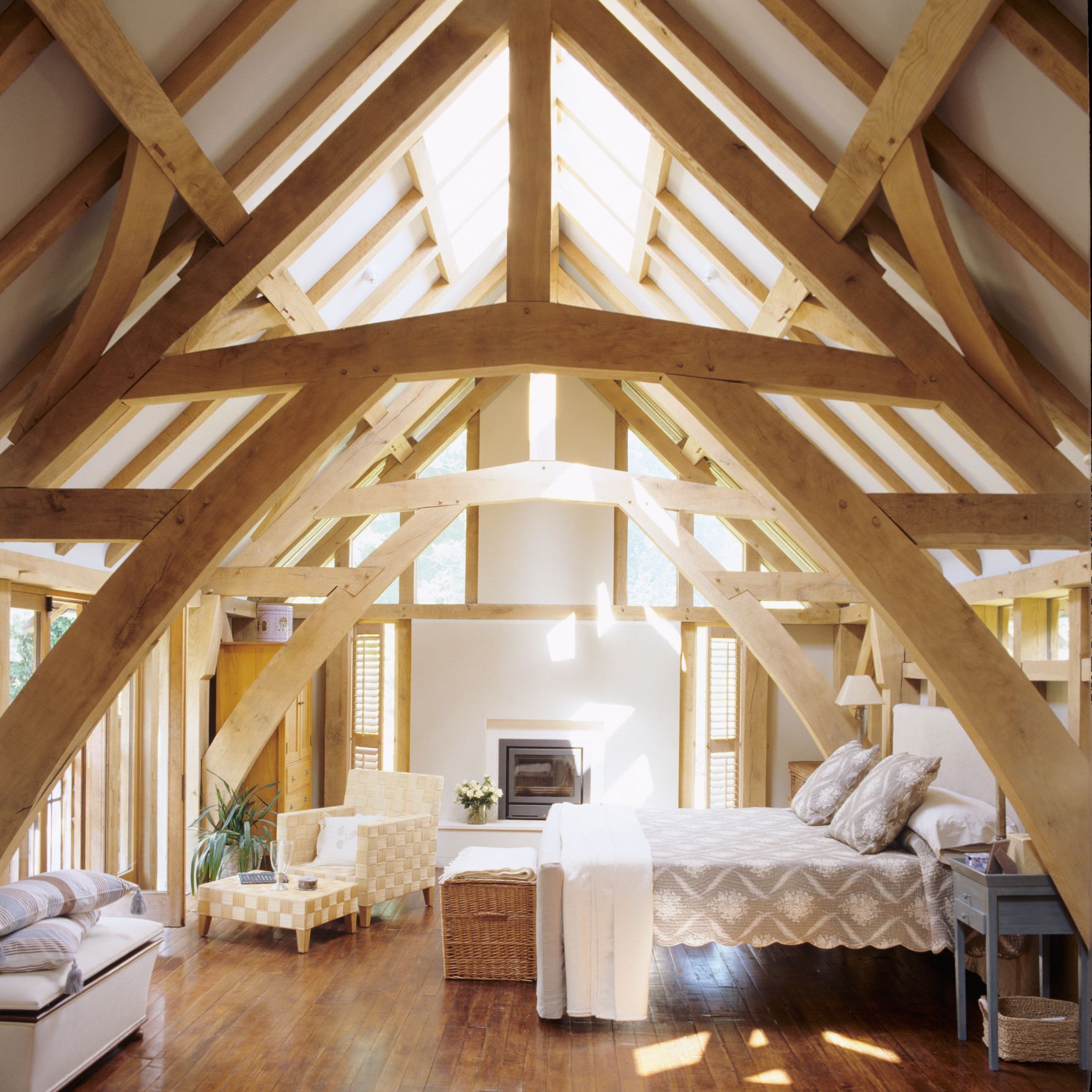 Interior of a white, open-concept room with large windows overlooking a beach and water.