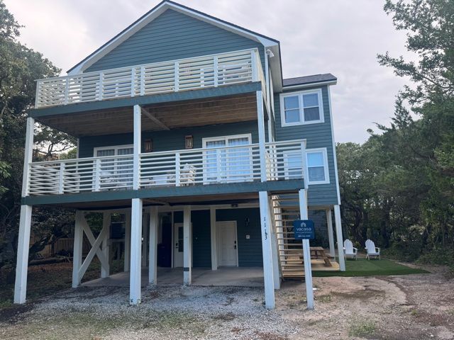 Blue beach house with white railing and multiple decks.