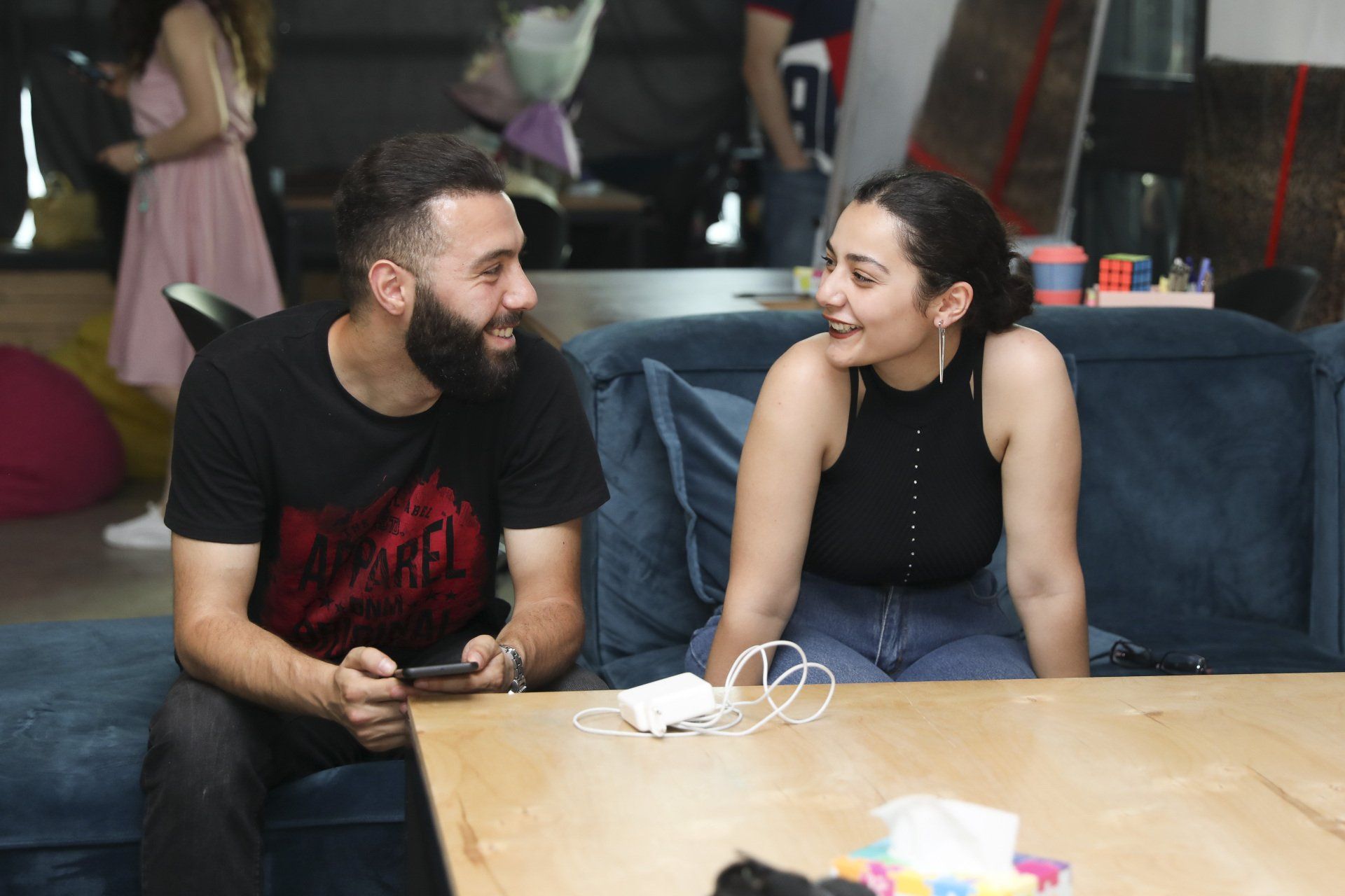 A man and a woman are sitting on a couch talking to each other.