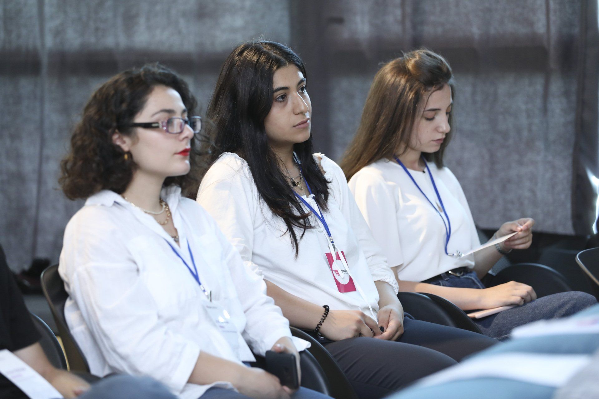A group of young women are sitting in a row in a lecture hall.
