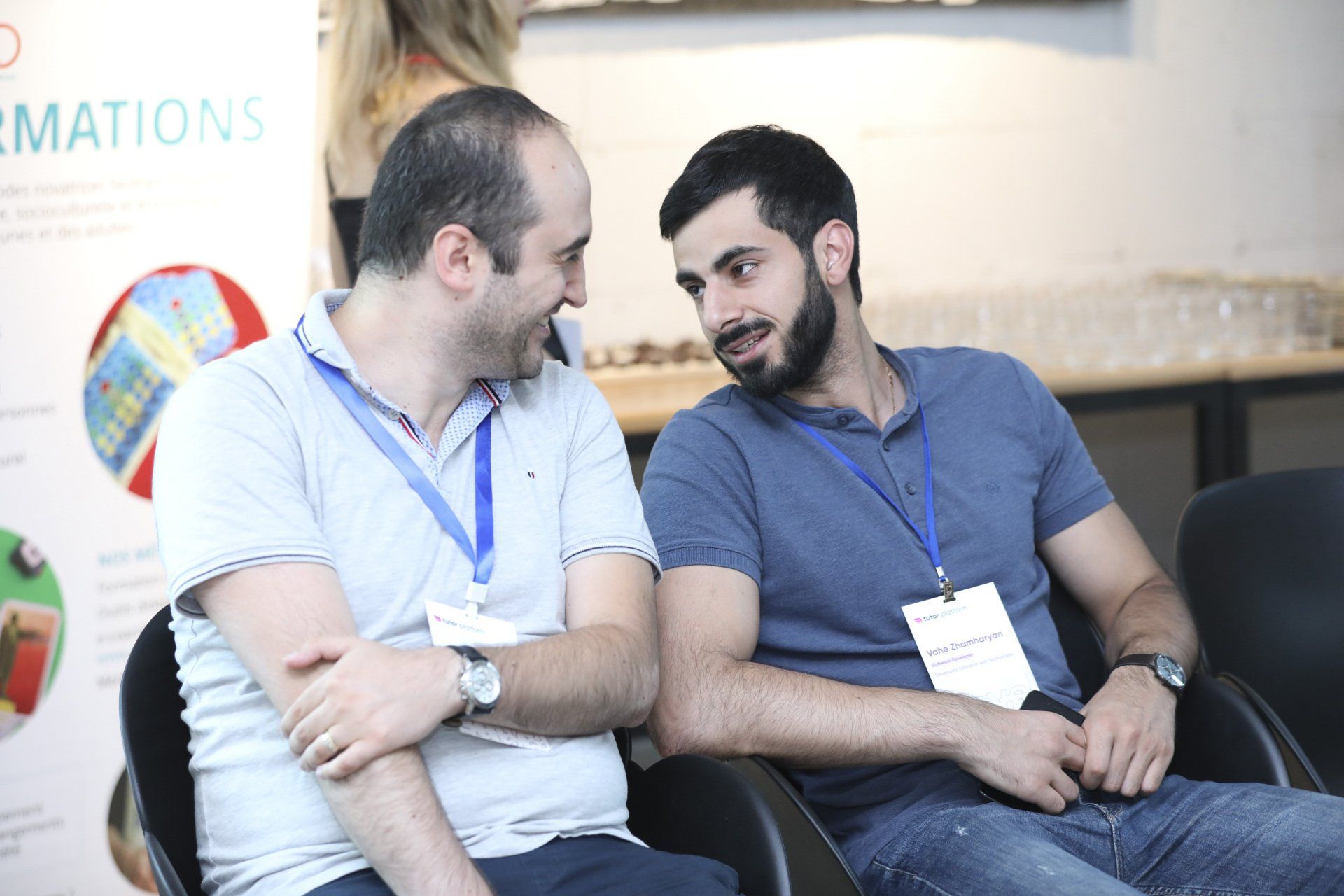 Two men are sitting in chairs talking to each other.