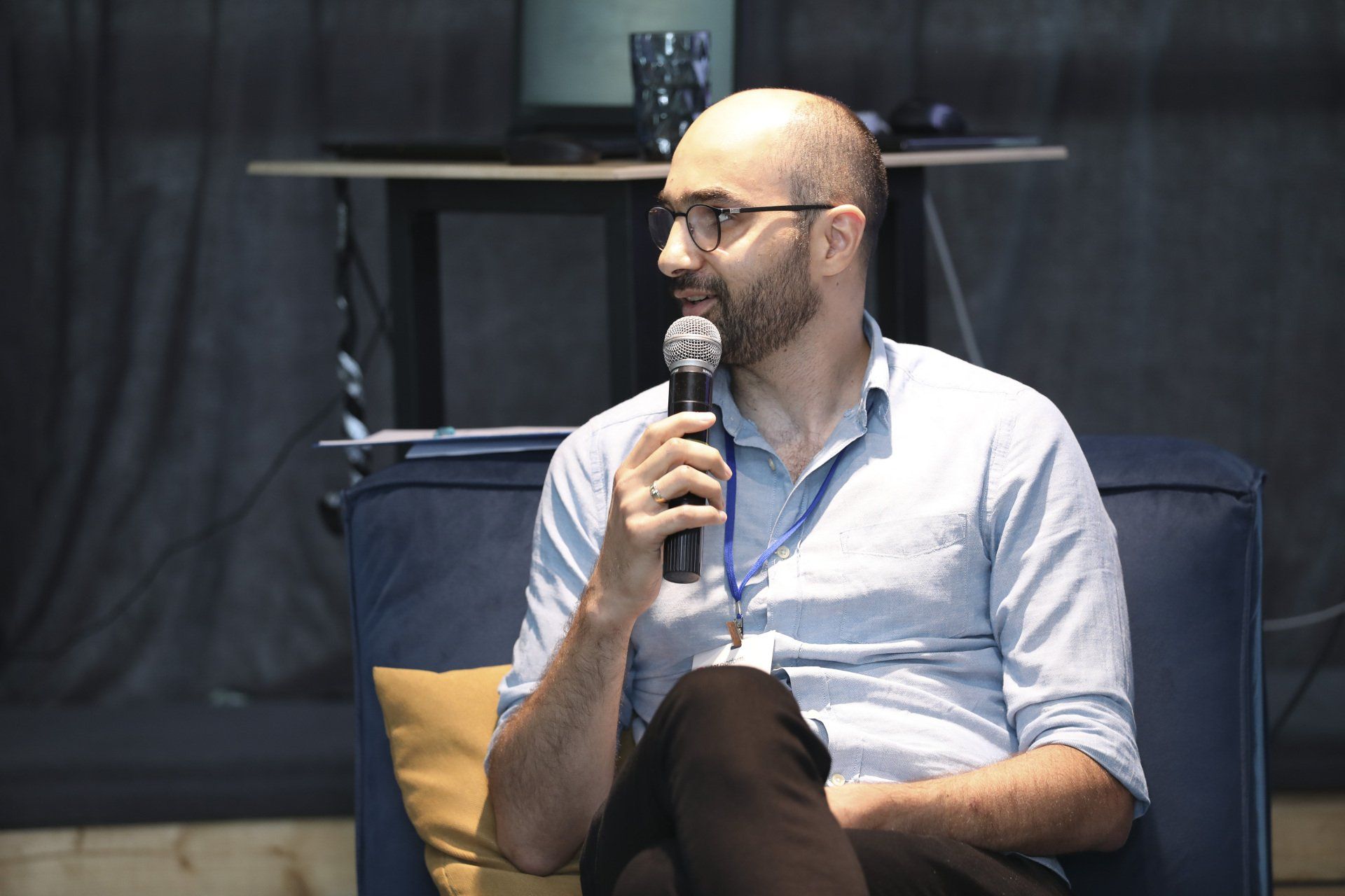 A man is sitting on a couch holding a microphone.