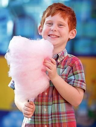 A Young Boy Is Holding A Cotton Candy Cone And Smiling — Rides N Slides In Townsville, QLD
