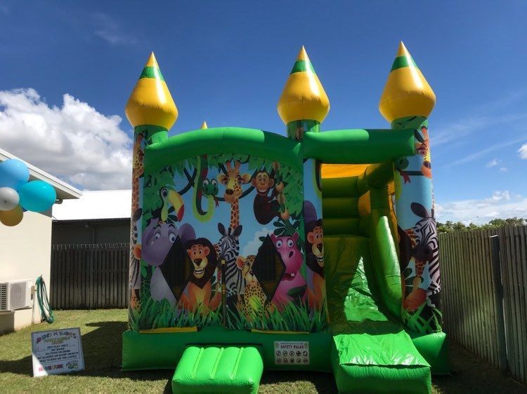 A Green And Yellow Bouncy House With Animals On It — Rides N Slides In Townsville, QLD