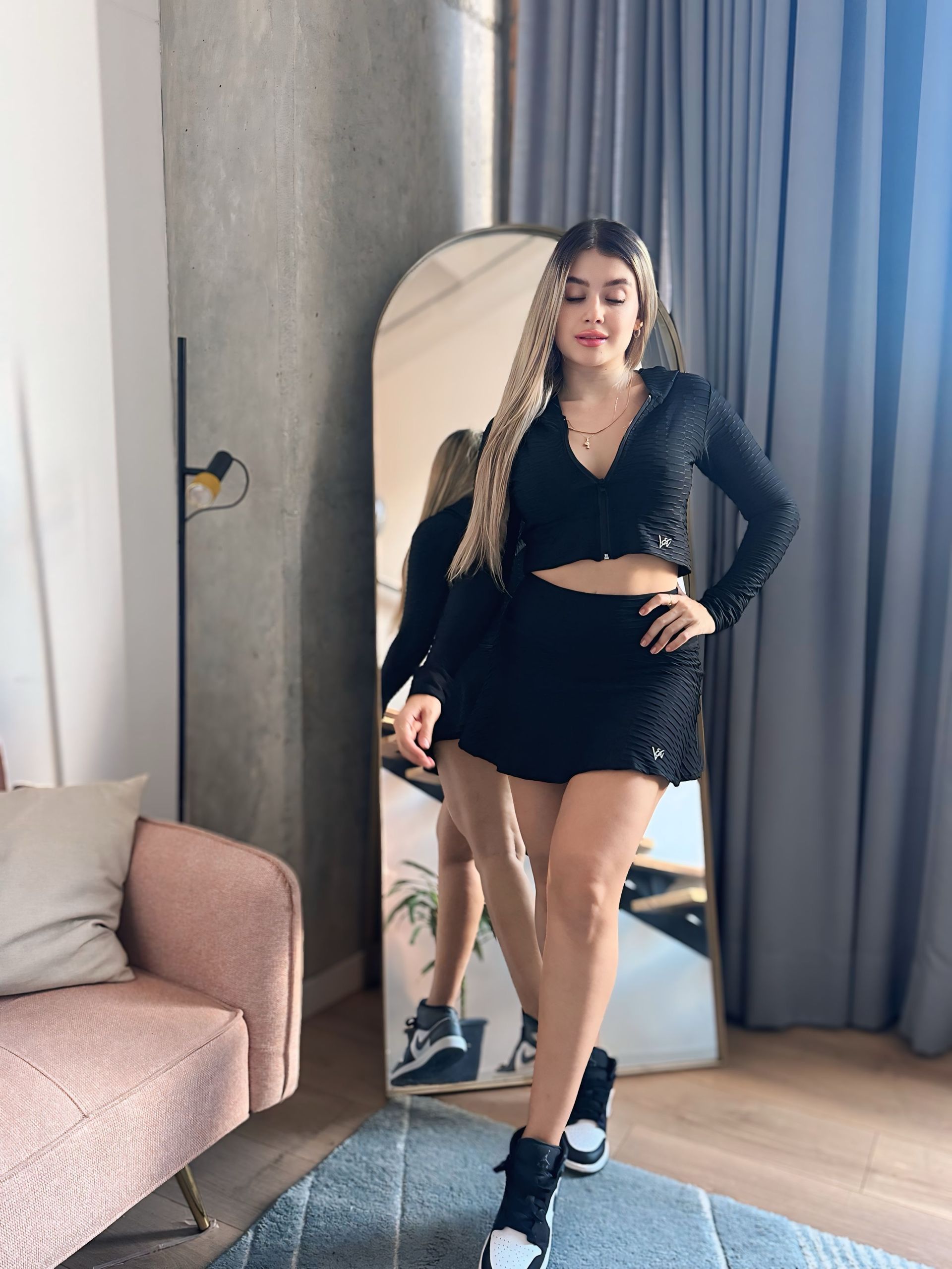 A woman is standing in front of a large mirror in a living room.