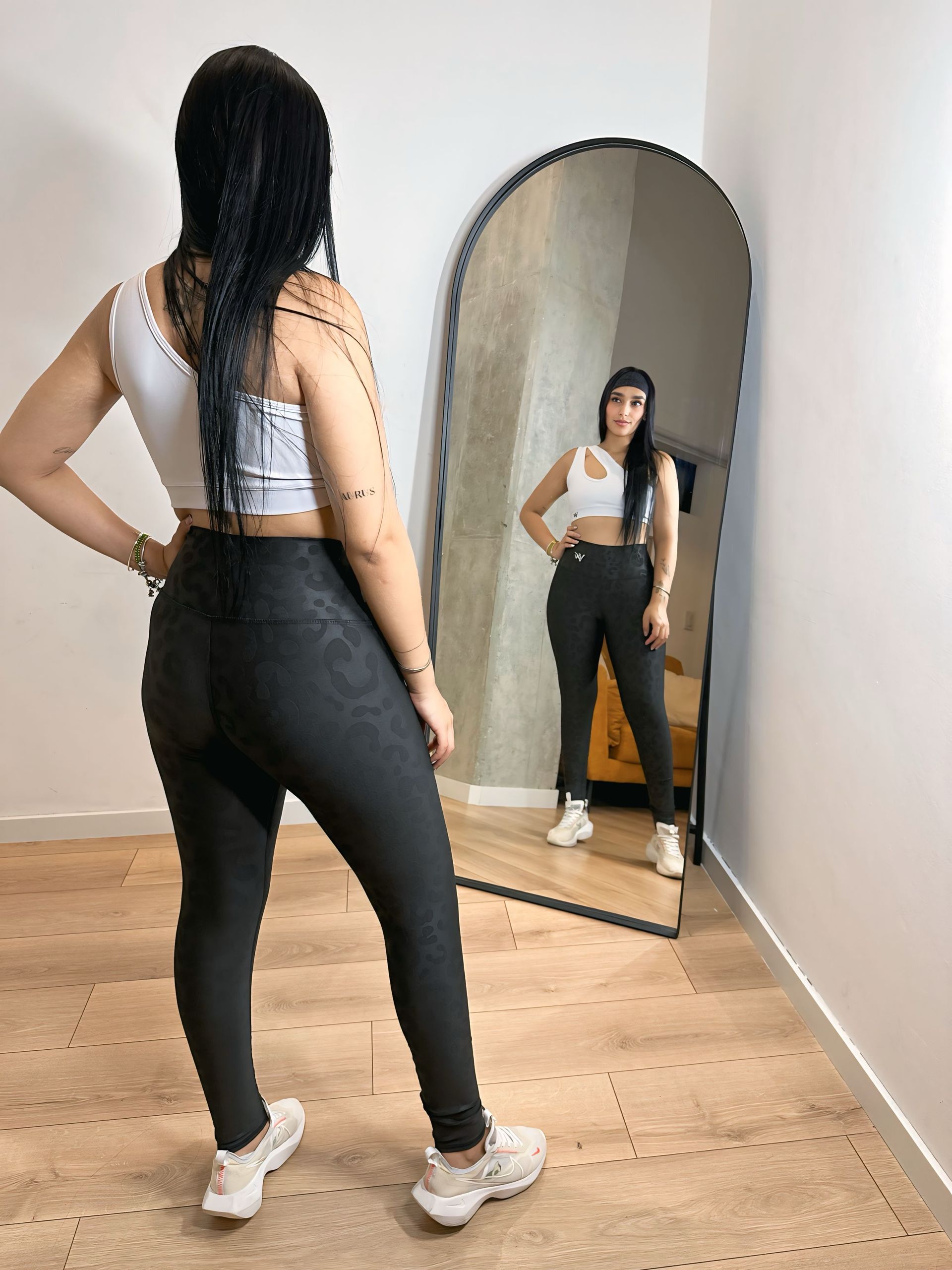 A woman is standing in front of a mirror in a room.