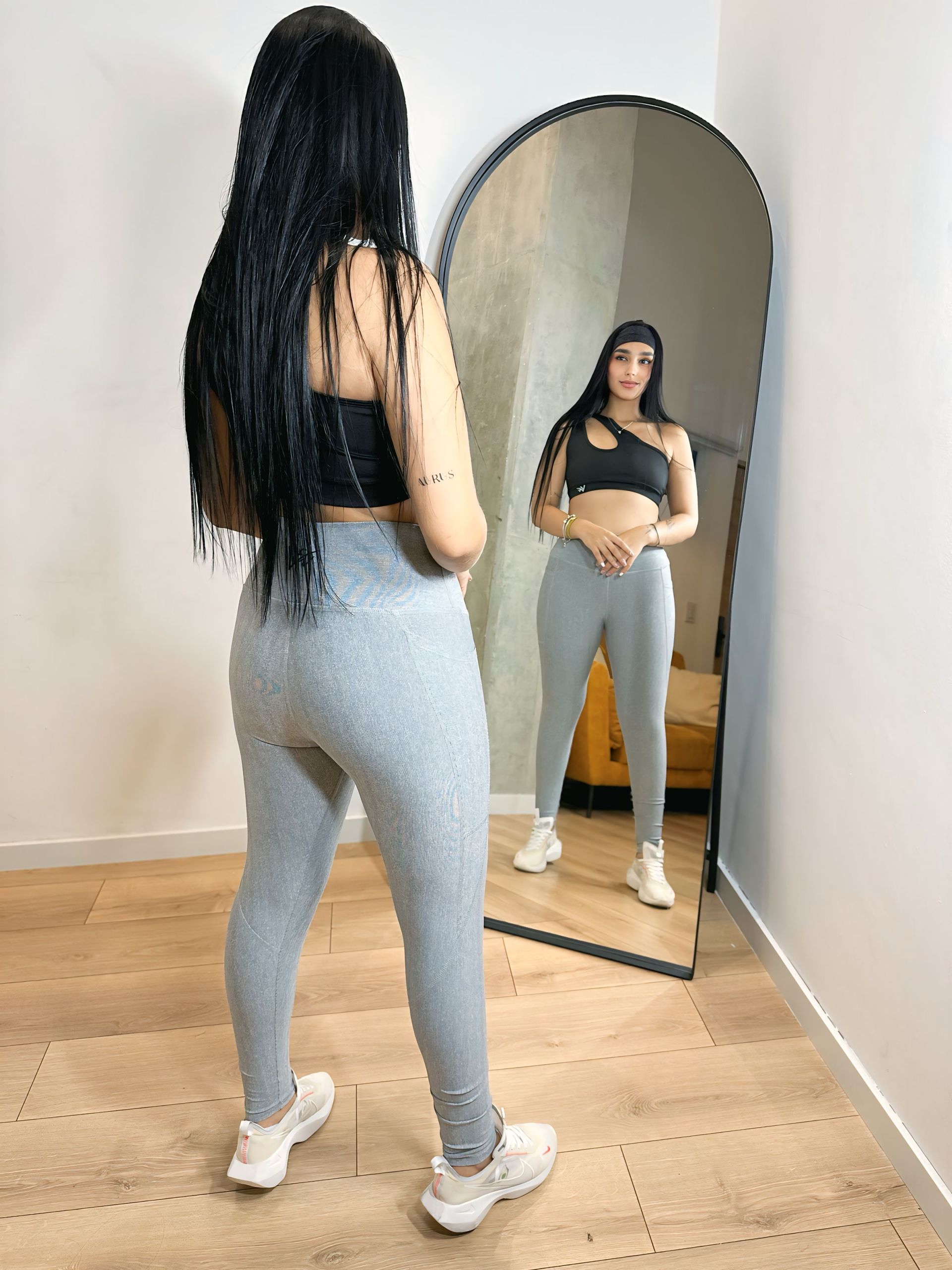 A woman is standing in front of a full length mirror.