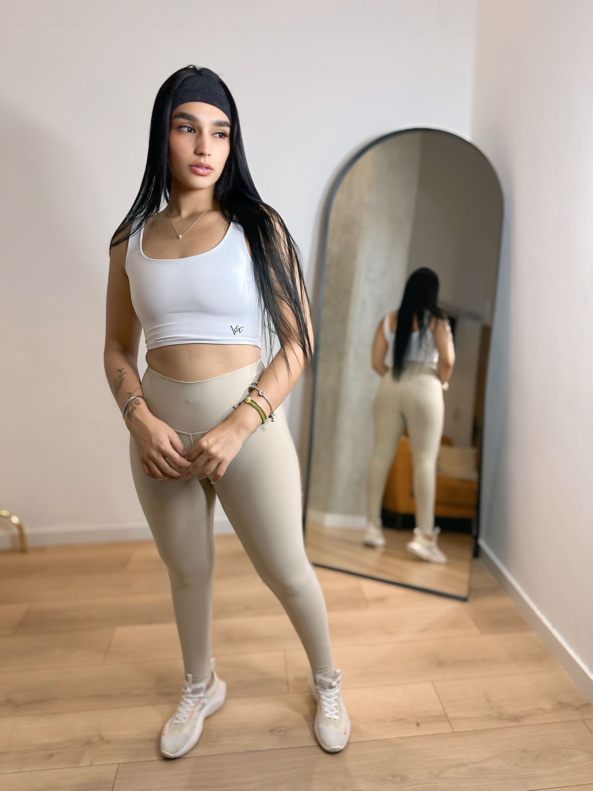 A woman is standing in front of a mirror in a room.