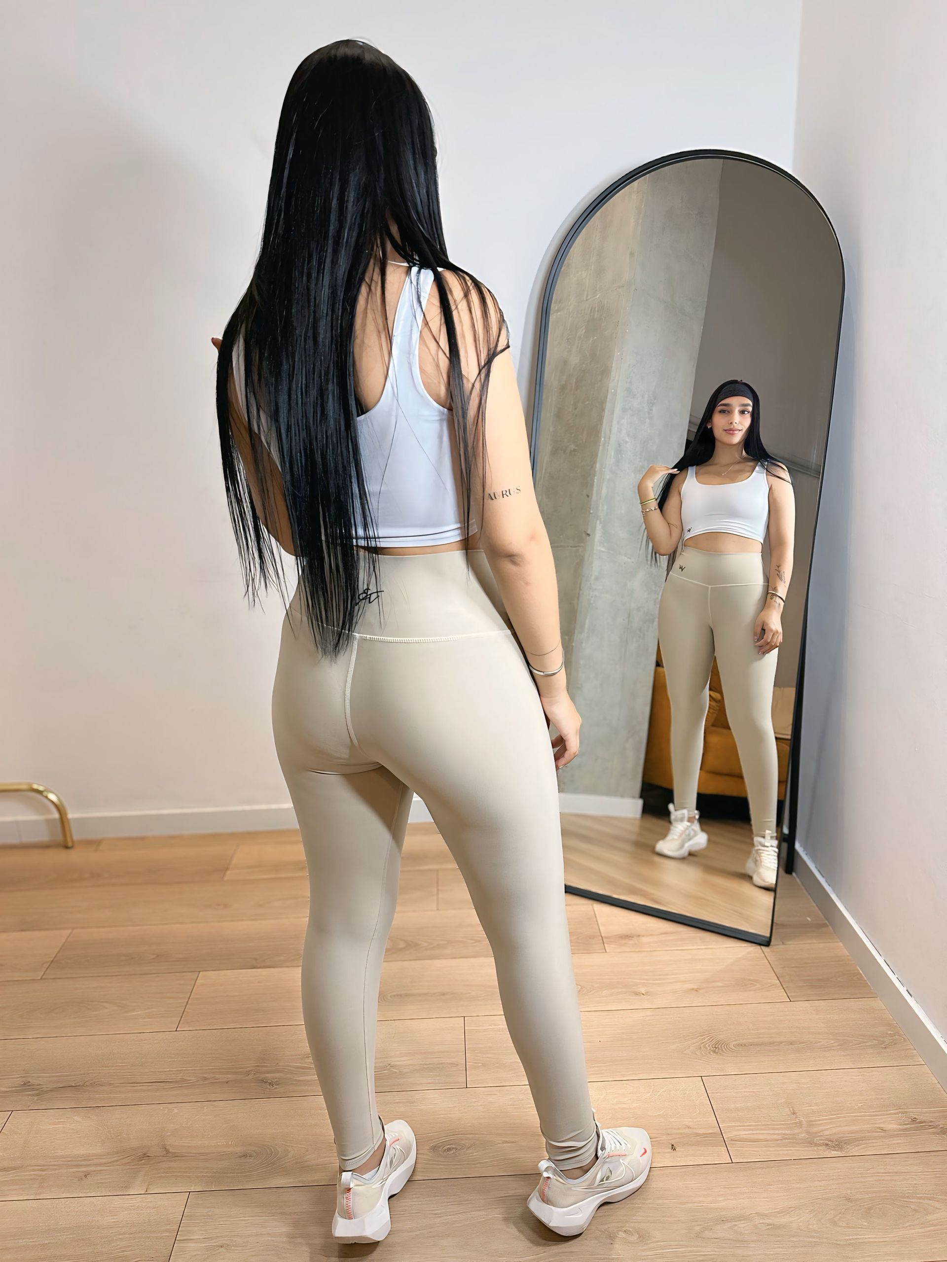 A woman is standing in front of a mirror in a room.