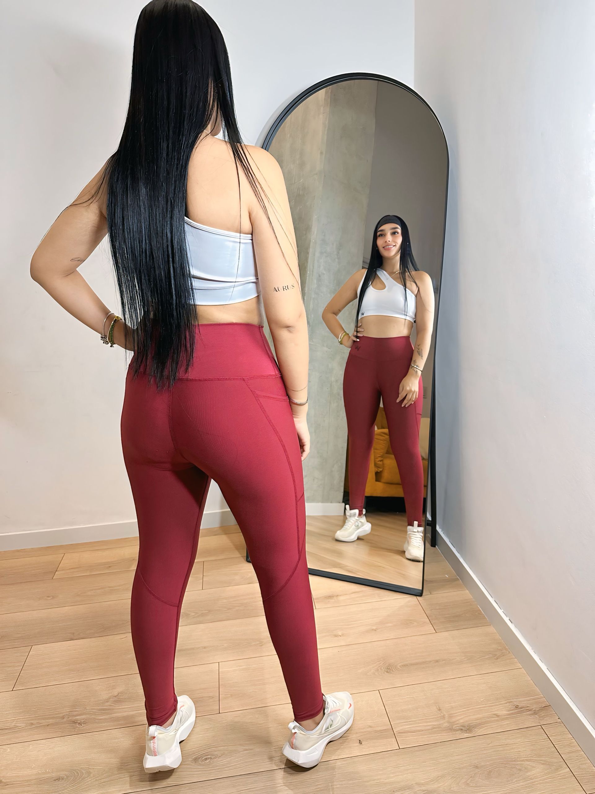 A woman is standing in front of a mirror in a room.