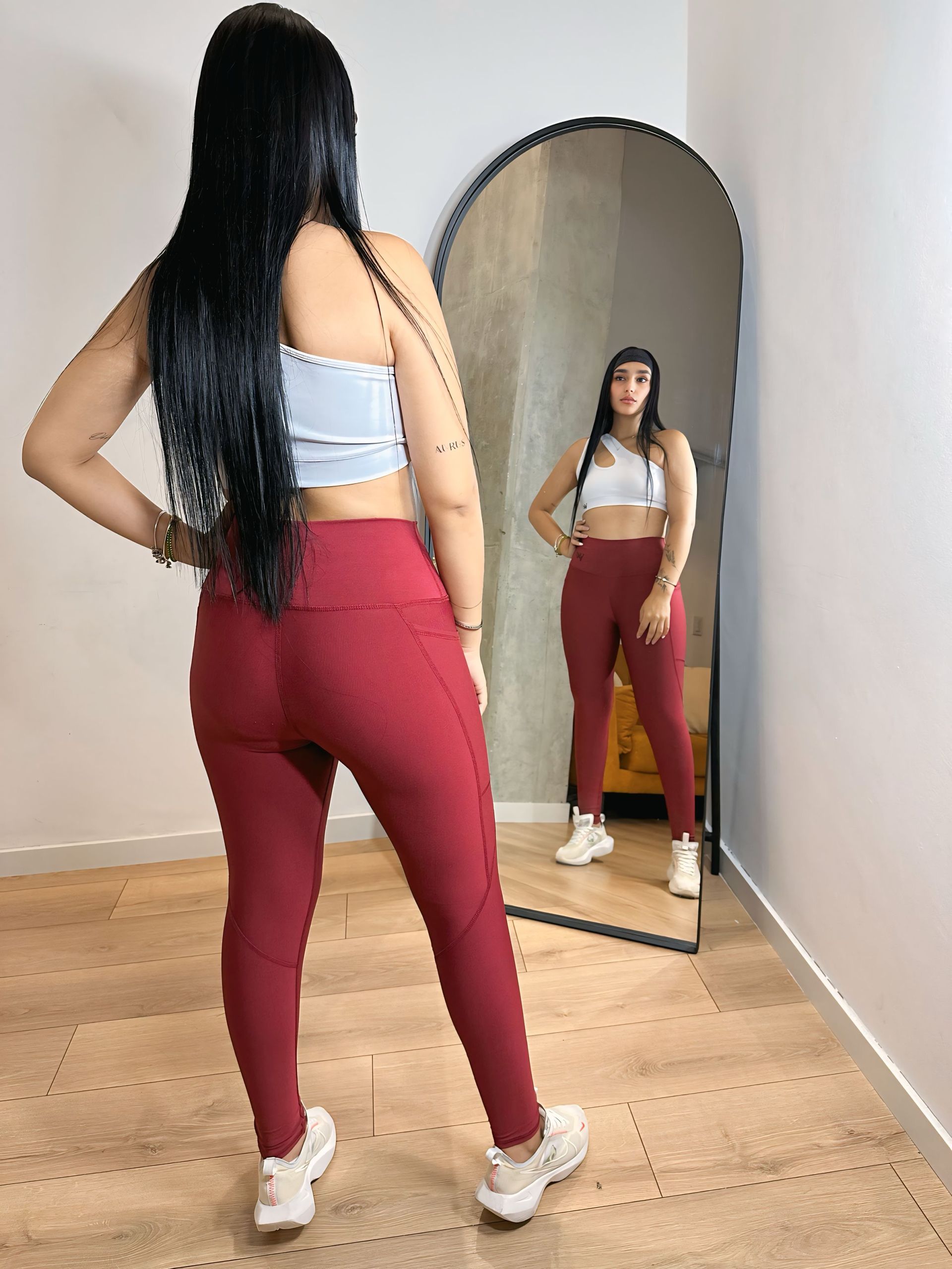 A woman is standing in front of a mirror in a room.