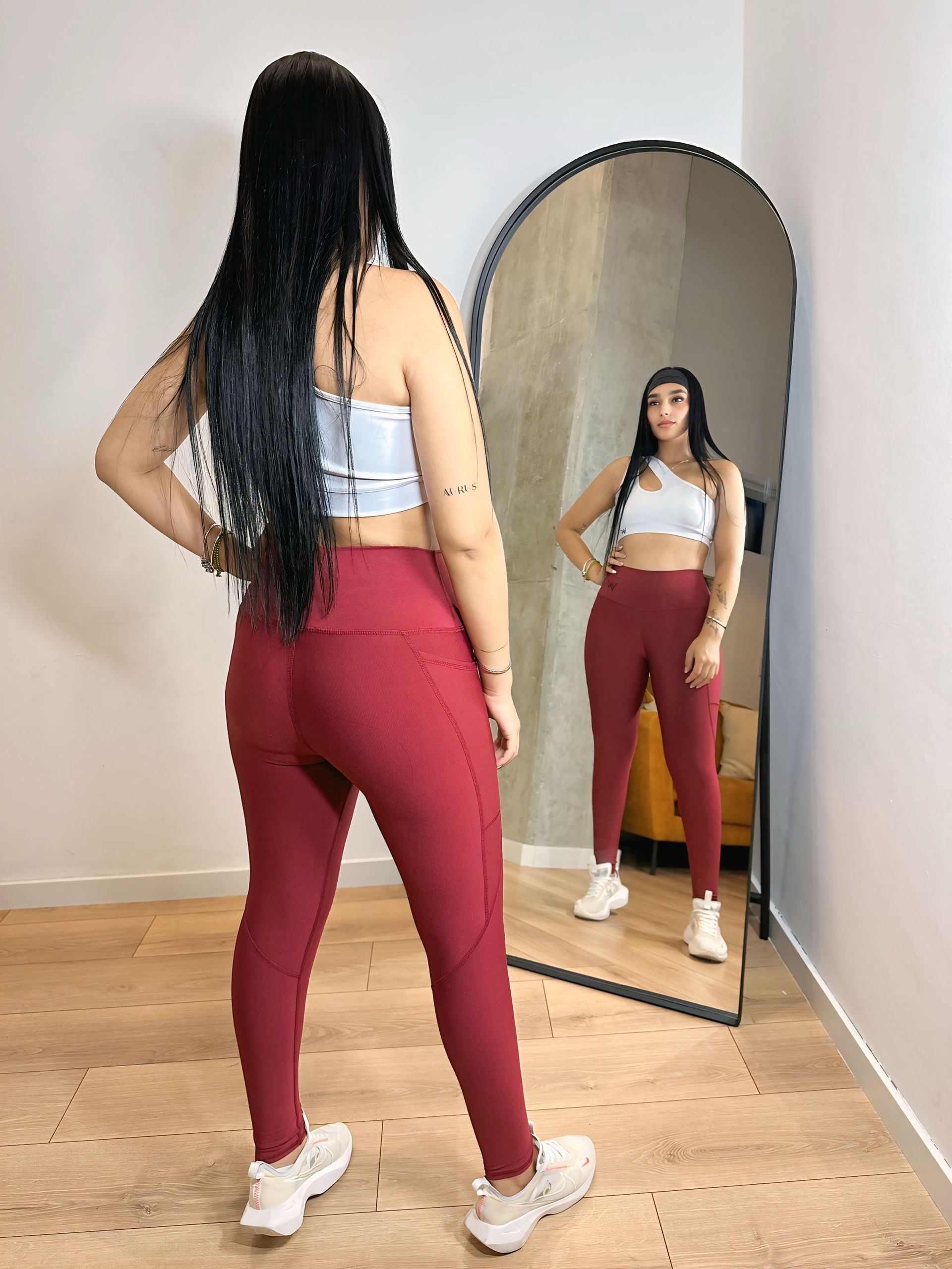 A woman is standing in front of a mirror wearing red leggings.