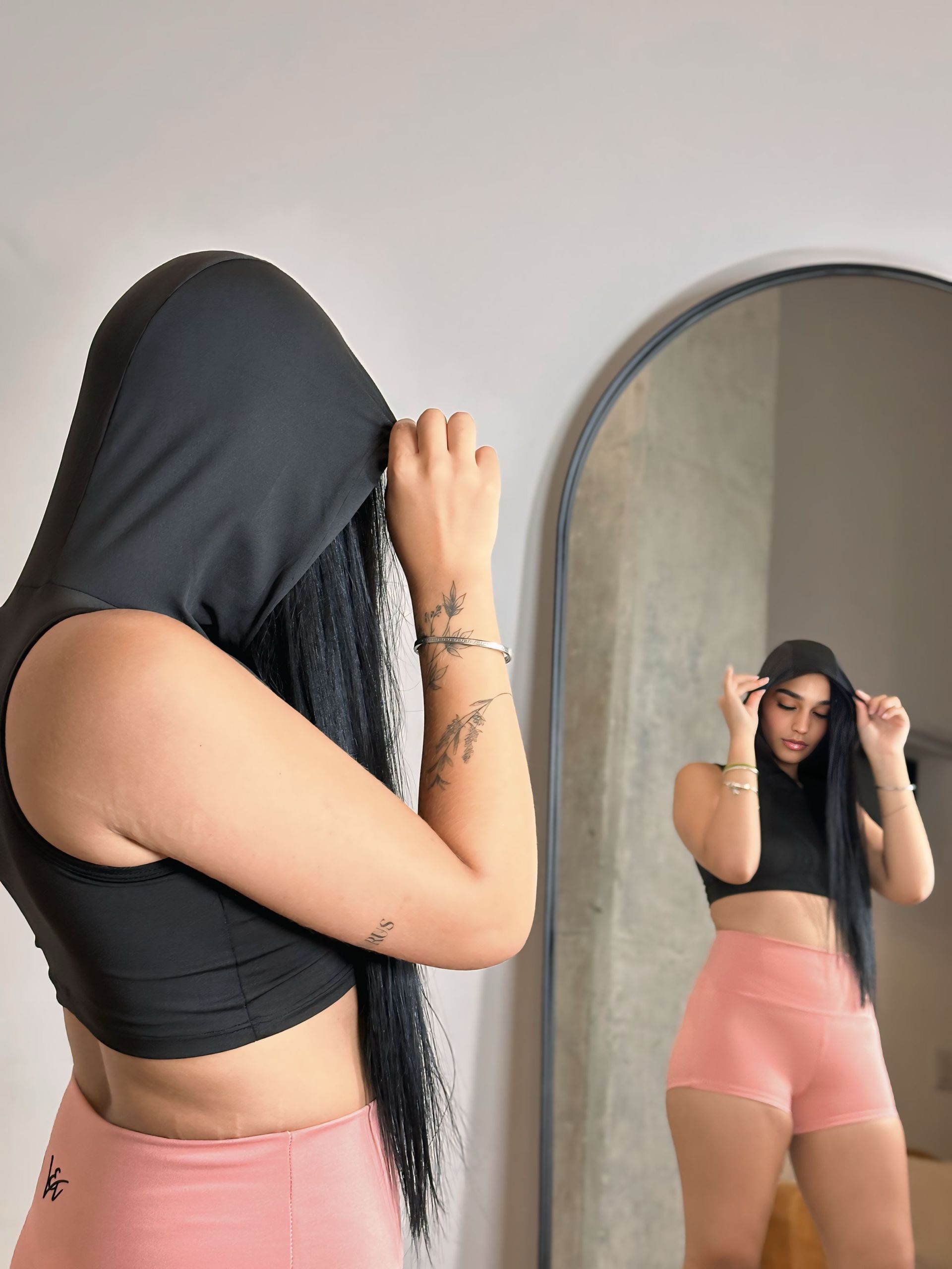 A woman is standing in front of a mirror covering her face with her hair