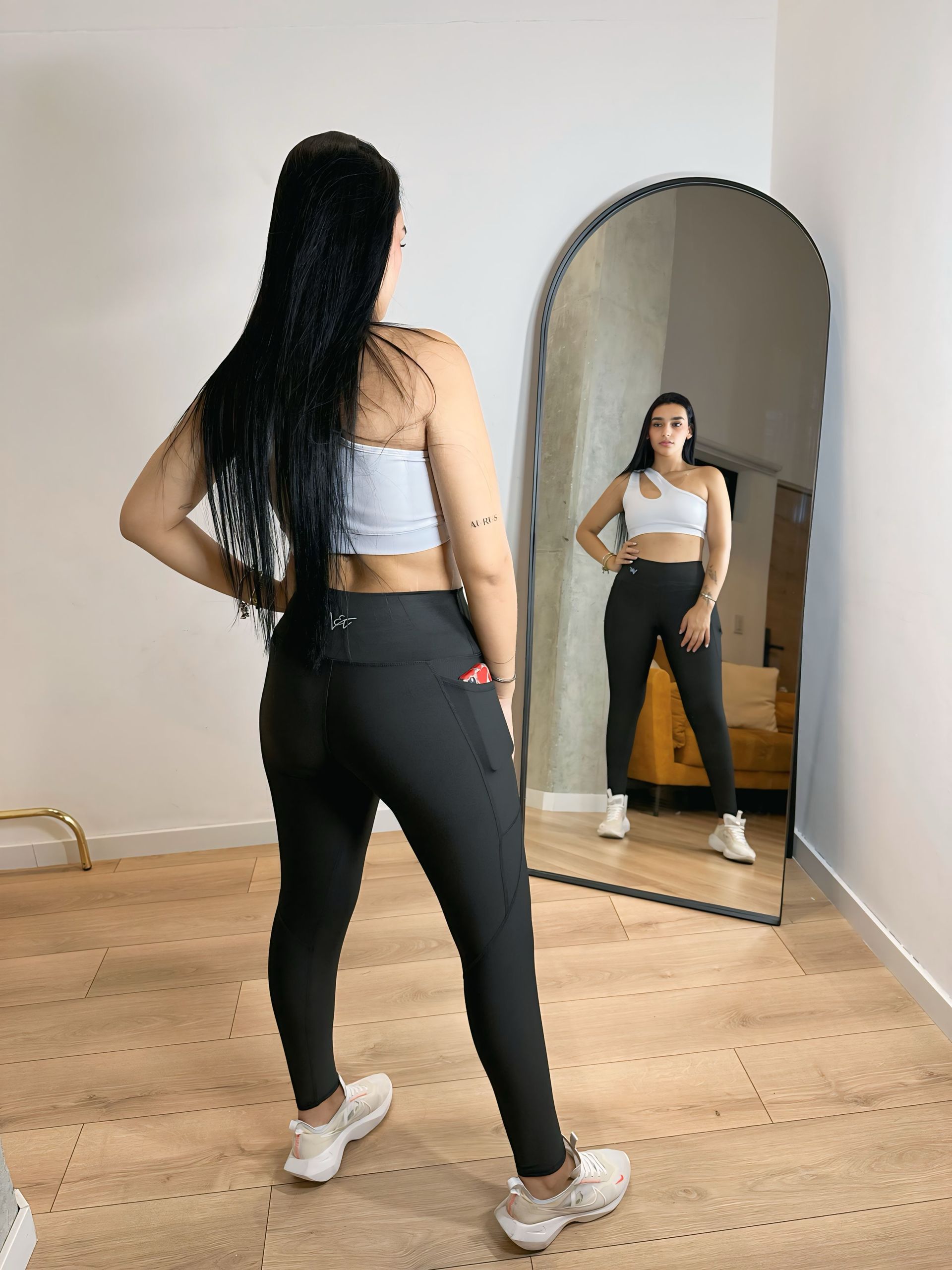 A woman is standing in front of a mirror in a room.