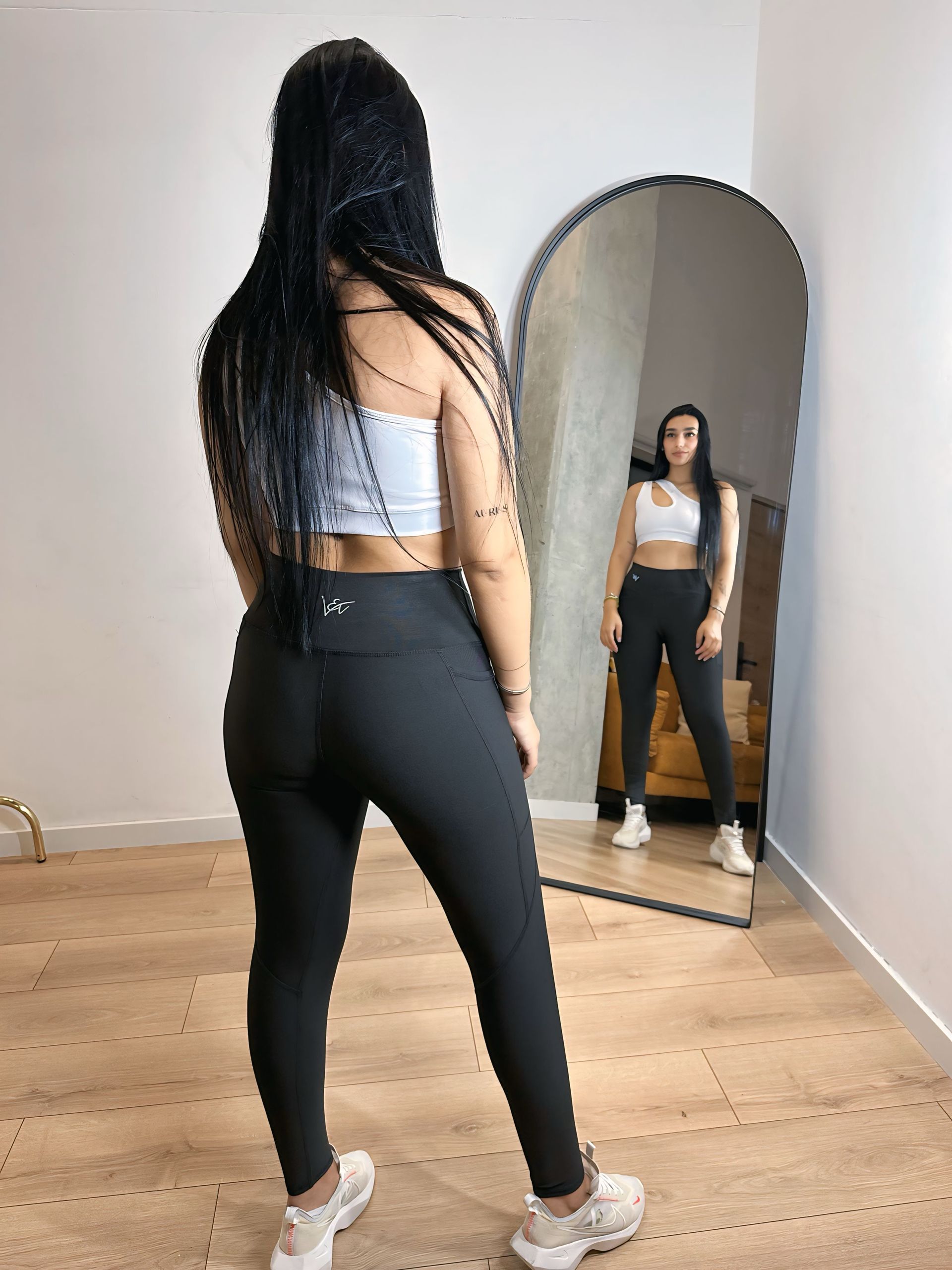 A woman is standing in front of a mirror in a room.
