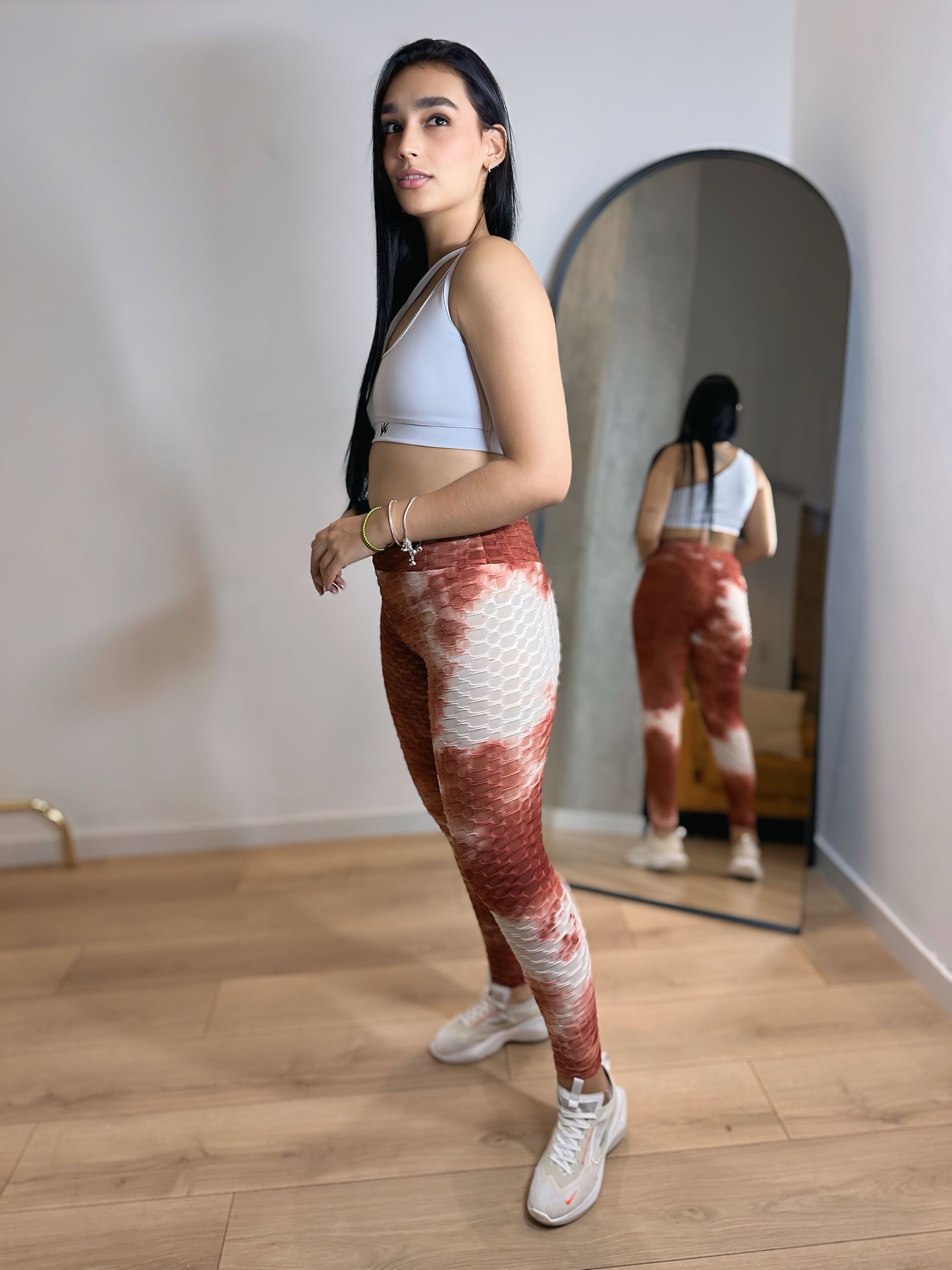 A woman is standing in front of a mirror in a room.