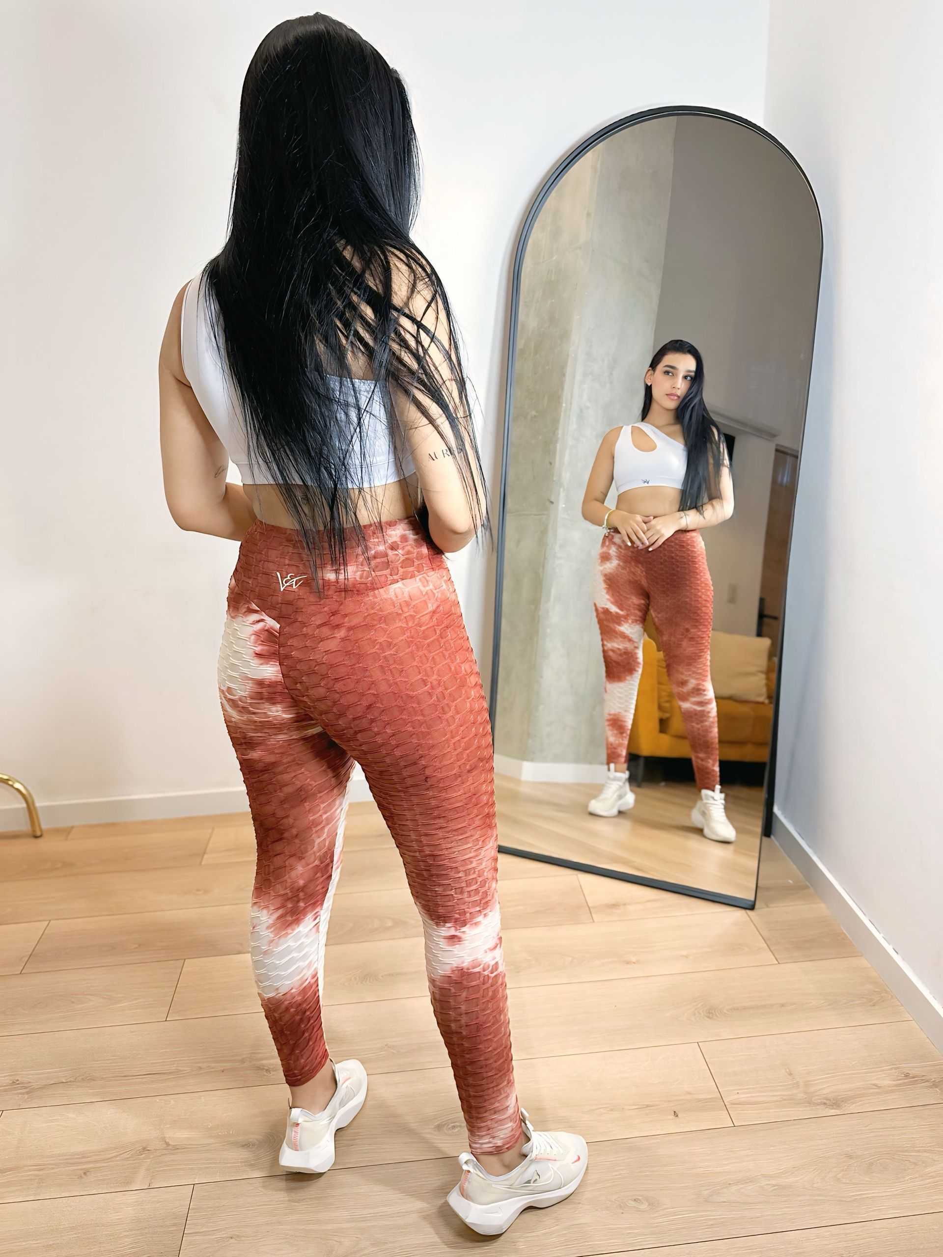 A woman is standing in front of a mirror in a room.