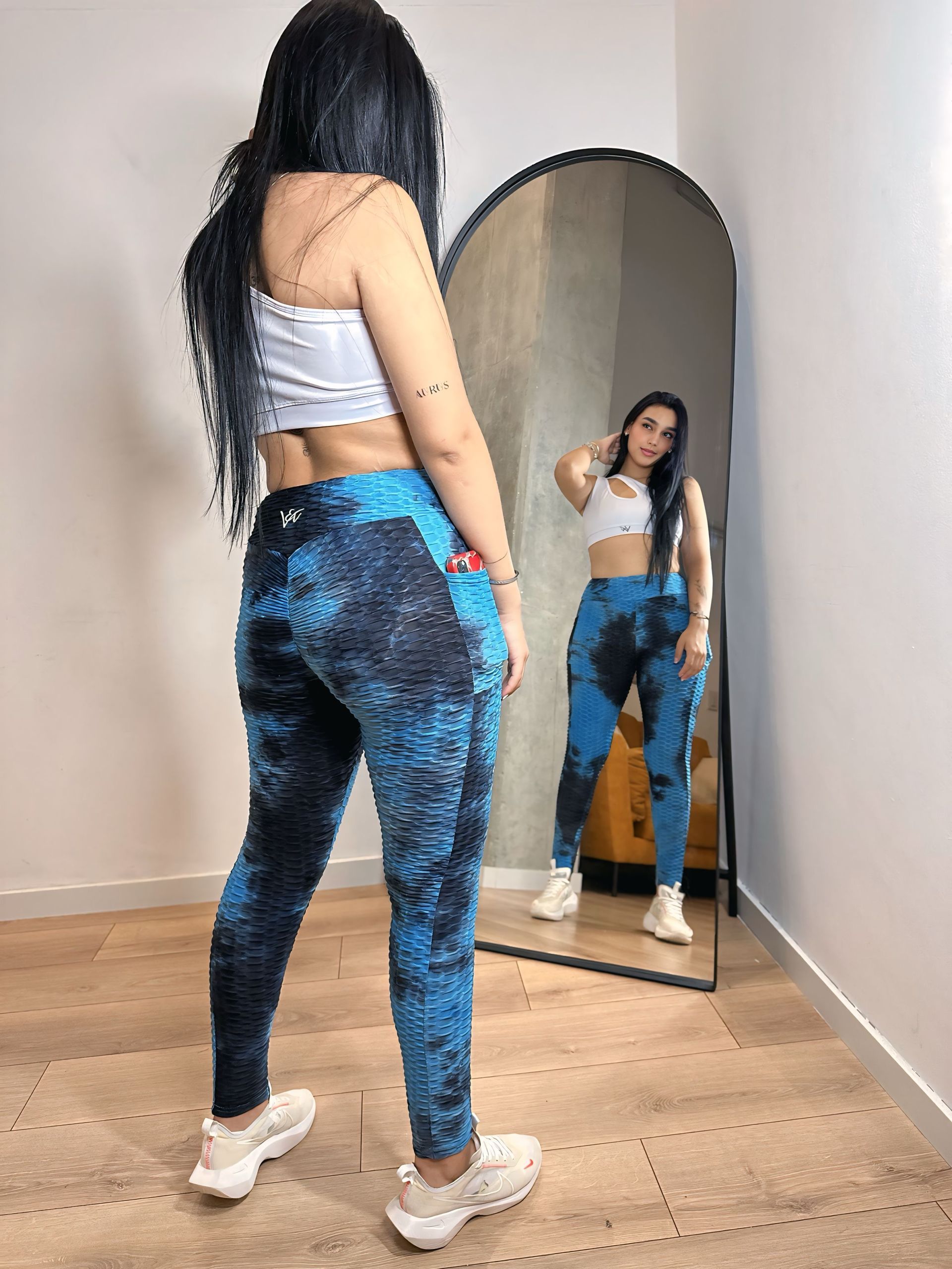 A woman is standing in front of a mirror wearing blue leggings.