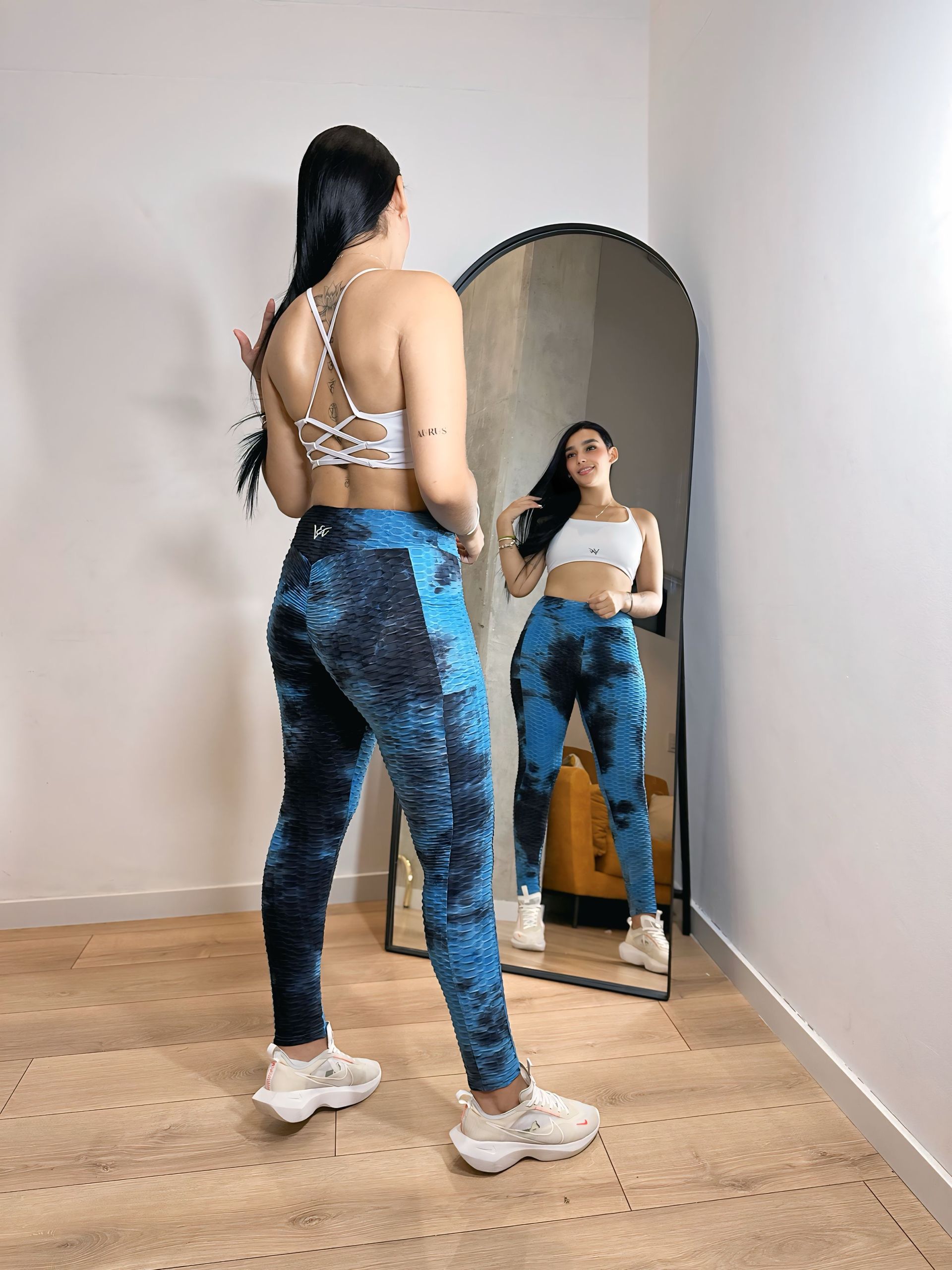 A woman is standing in front of a mirror in a room.