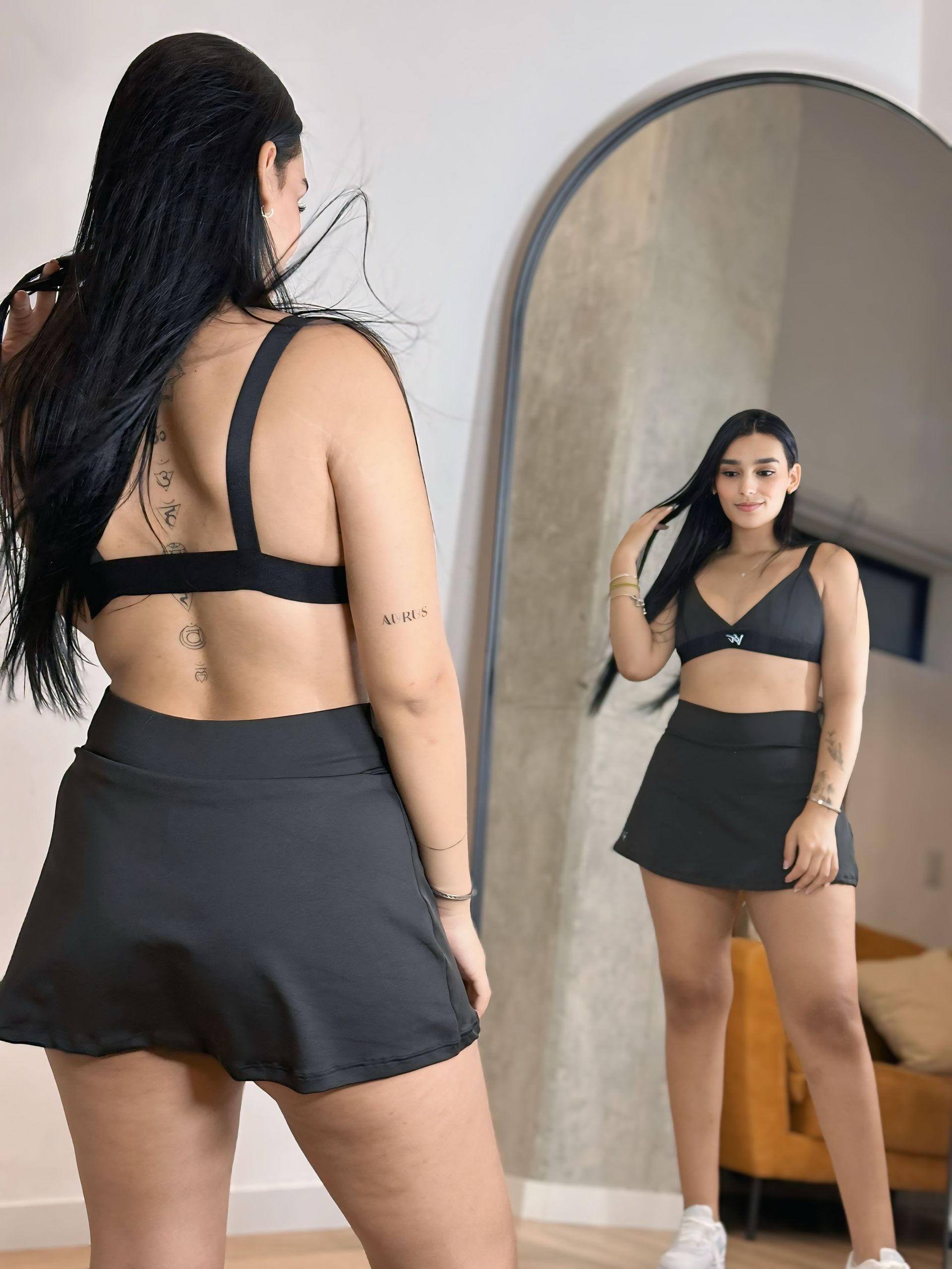 A woman is standing in front of a mirror looking at herself.