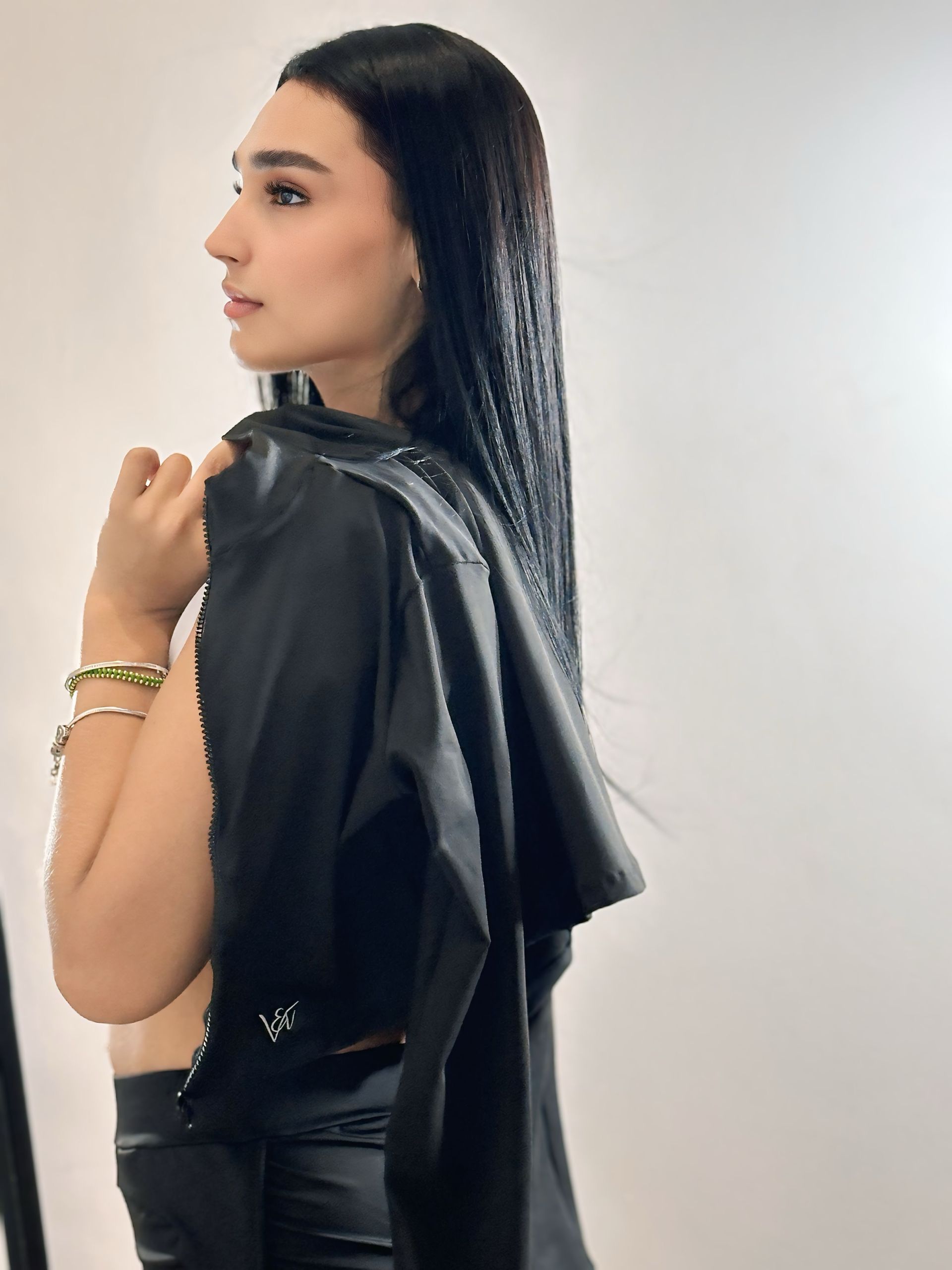 A woman is wearing a black leather jacket over her shoulder.
