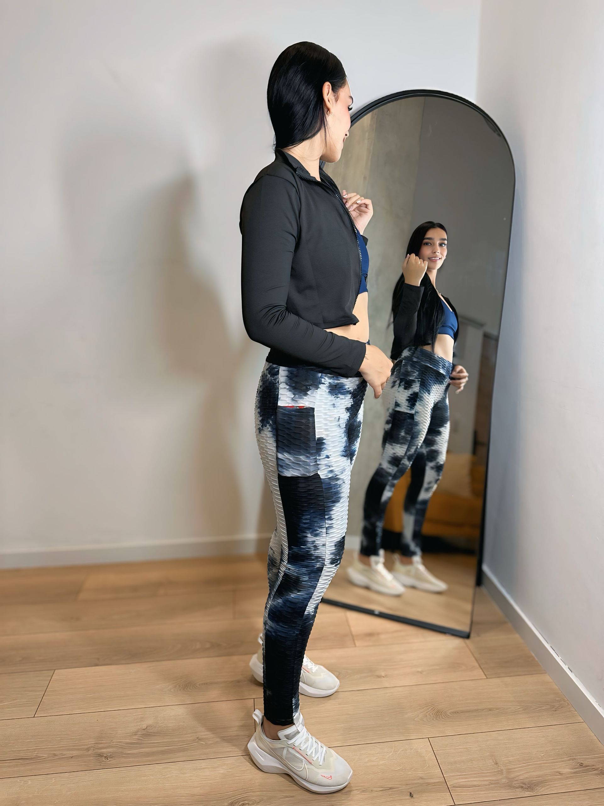 A woman is standing in front of a mirror in a room.