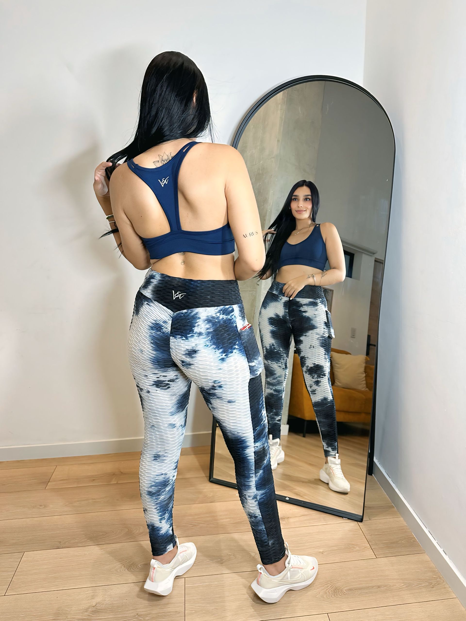 A woman is standing in front of a mirror in a room.