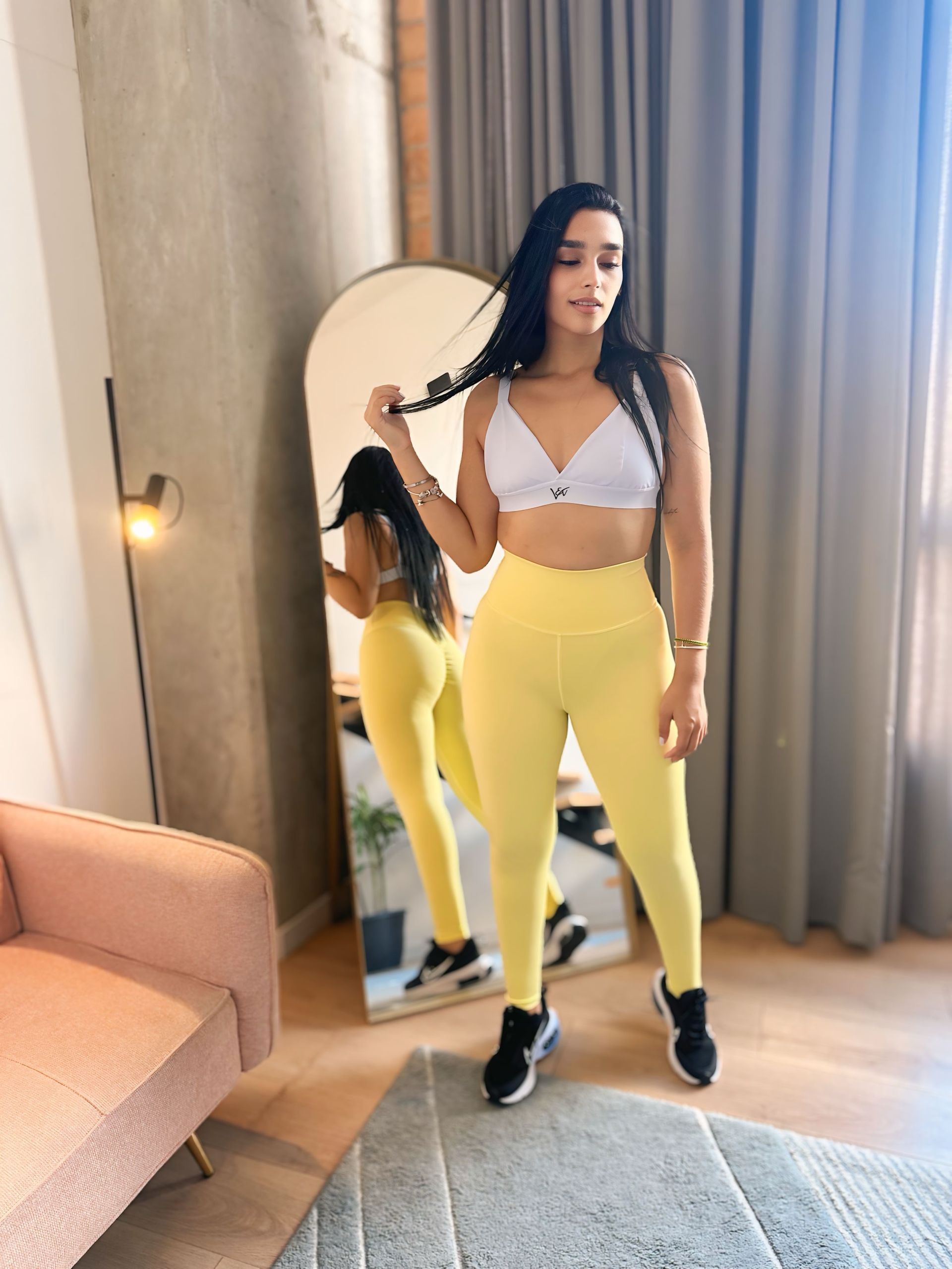A woman is standing in front of a mirror in a living room.