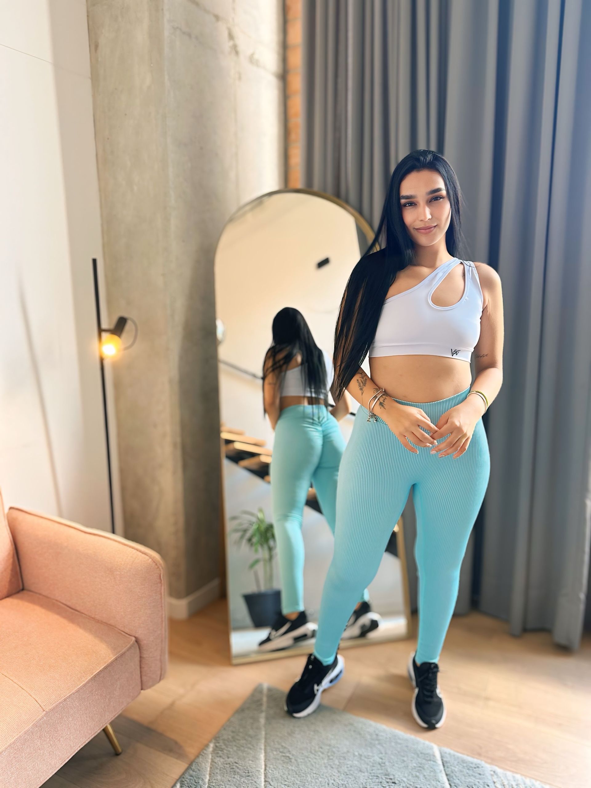 A woman is standing in front of a mirror in a room.